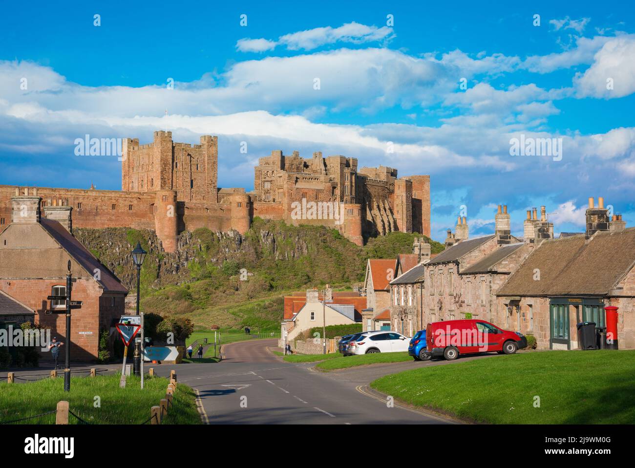 Bamburgh village, view in summer of Front Street in Bamburgh with the castle sited dramatically above the village, Northumberland, England, UK Stock Photo