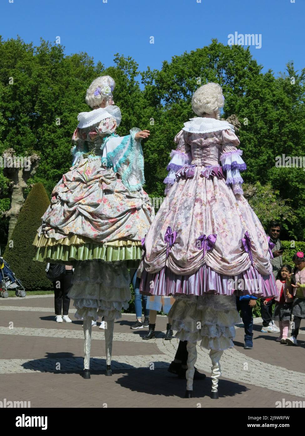 Entertainment for the crowds when two girls on tall stilts, wearing historical costume & wigs walk through the gardens at Keukenhof 2022. Stock Photo