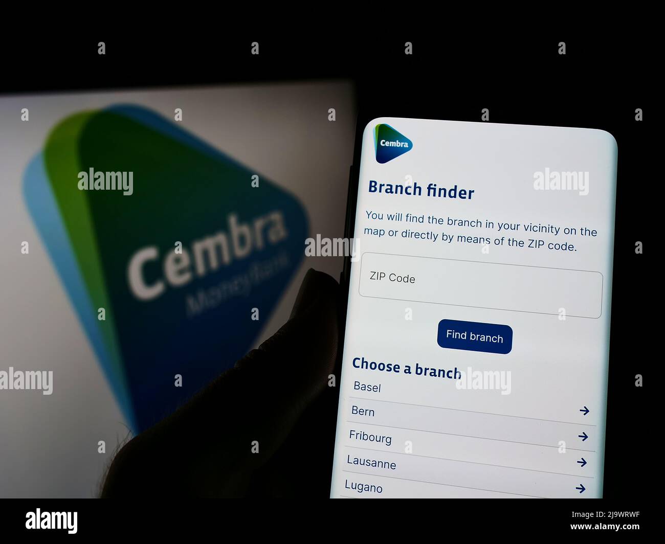 Person holding cellphone with webpage of Swiss financial company Cembra