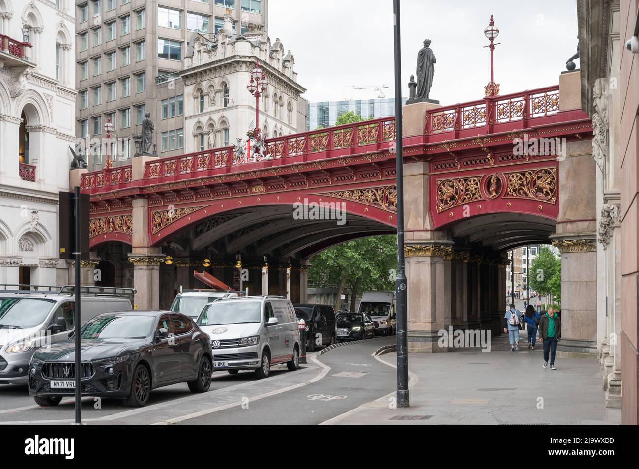 Road traffic passes under Holborn Viaduct, an ornate cast iron road bridge crossing Farringdon Street. London, England, UK. Stock Photo