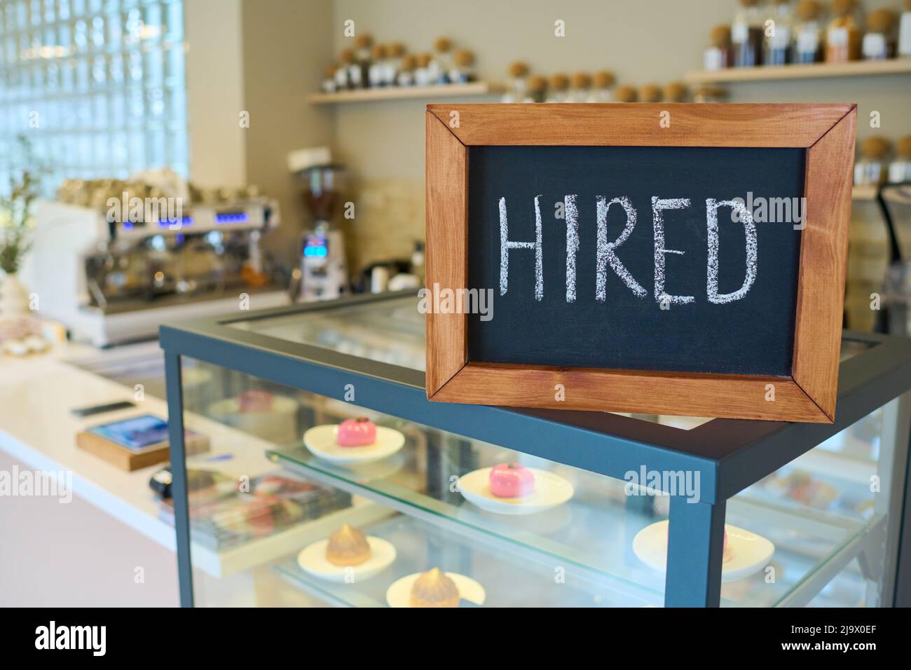 Close-up of chalkboard with hired sign standing on counter in coffee shop Stock Photo