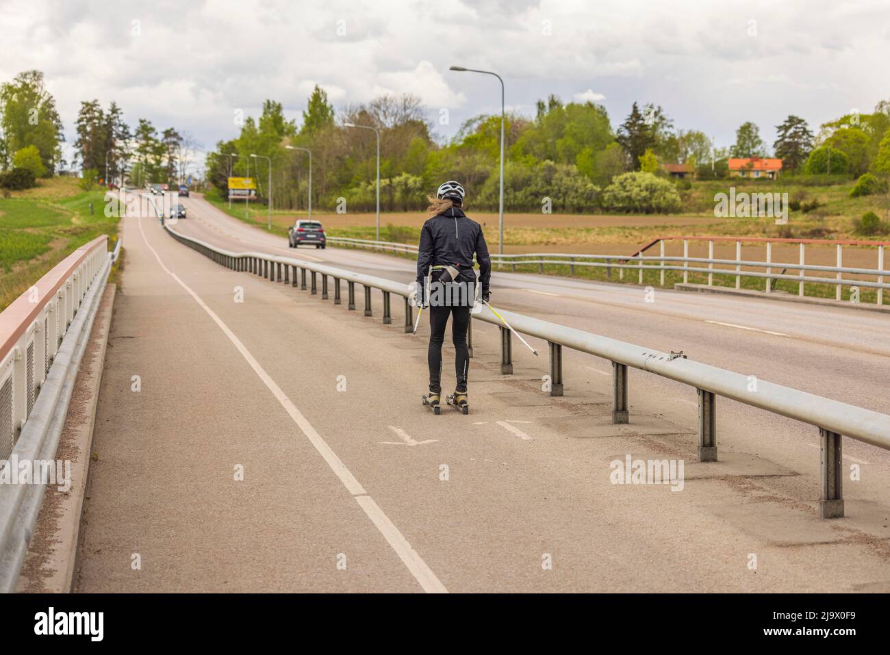 Man trains on roller skis on dedicated bike path on summer day. Concept of sports, healthy lifestyle. Sweden. Stock Photo