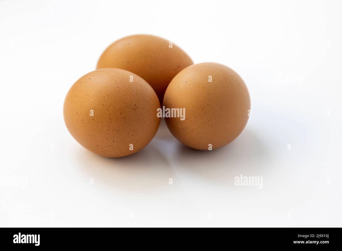 Chicken eggs on a white background, close up, three raw eggs. Stock Photo