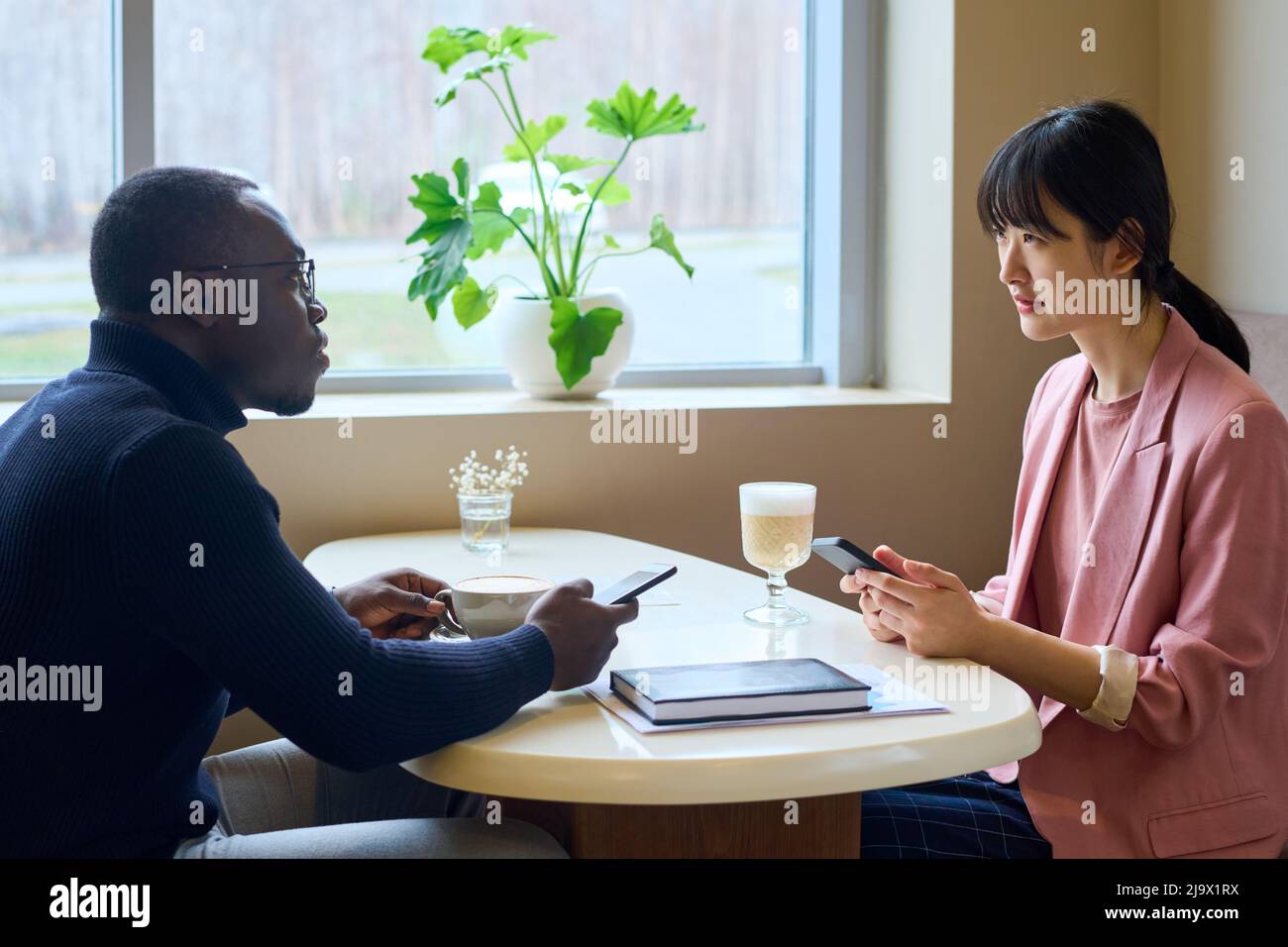 Two business partners exchanging phone numbers while drinking coffee at