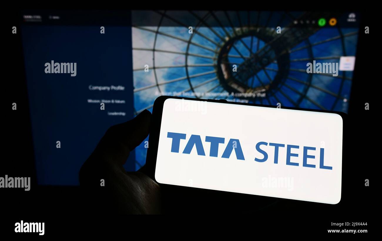 Person holding smartphone with logo of Indian steelmaking company Tata Steel Limited on screen in front of website. Focus on phone display. Stock Photo