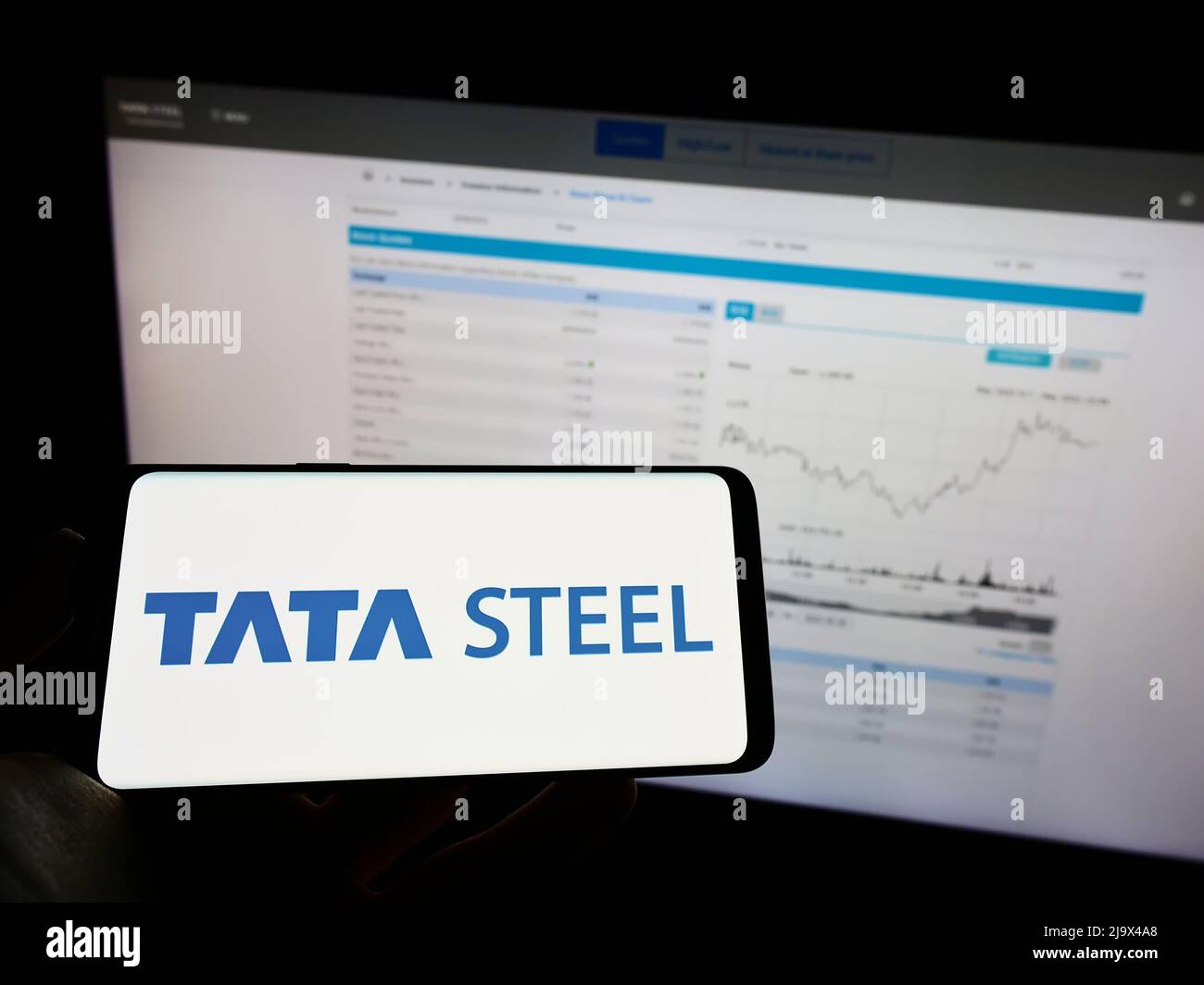 Person holding mobile phone with logo of Indian steelmaking company Tata Steel Limited on screen in front of web page. Focus on phone display. Stock Photo