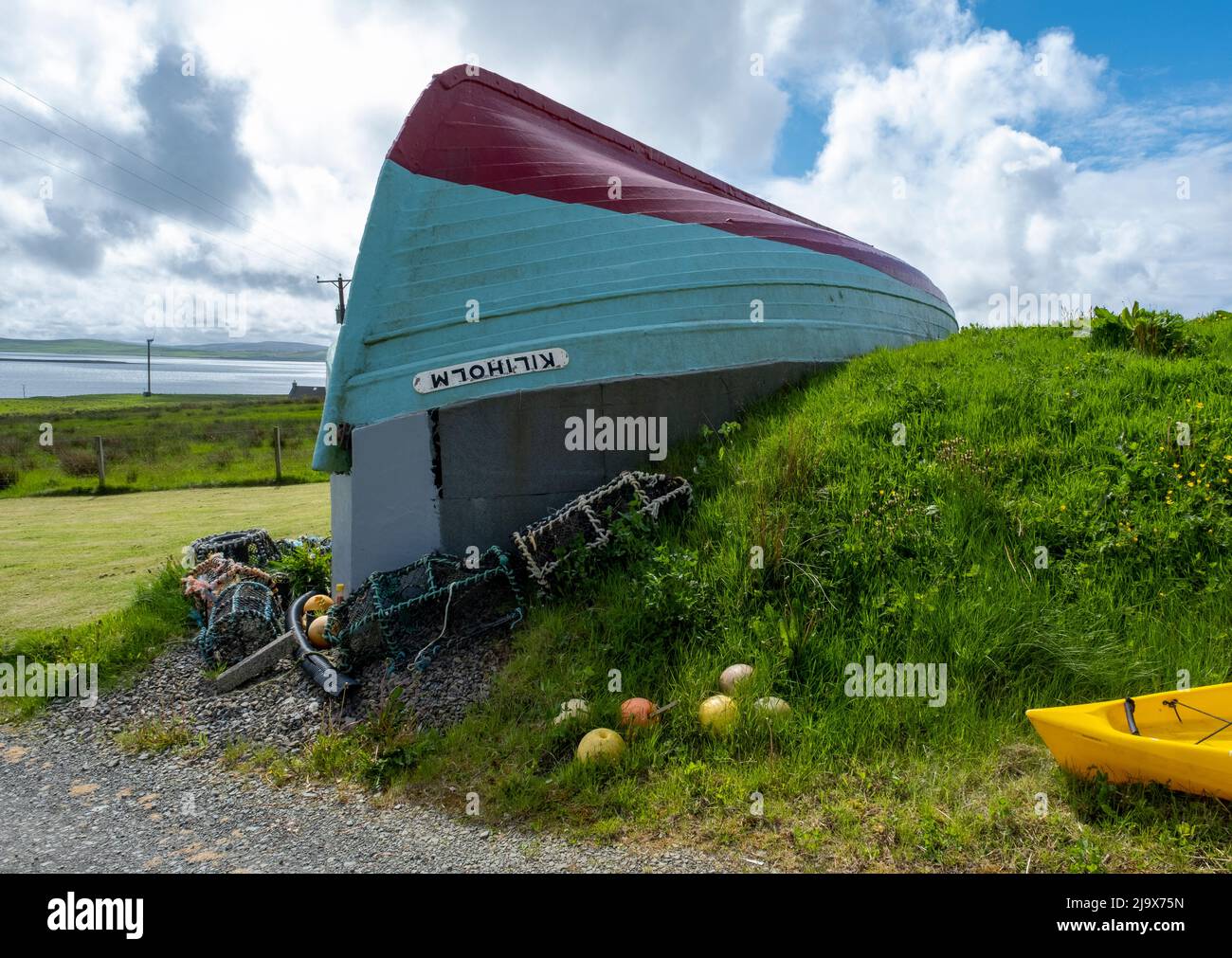 Quirky boathouse construction, Island of Rousay using an upturned fishing boat as a roof for a building with view over Wyre Sound, Orkney, Scotland. Stock Photo