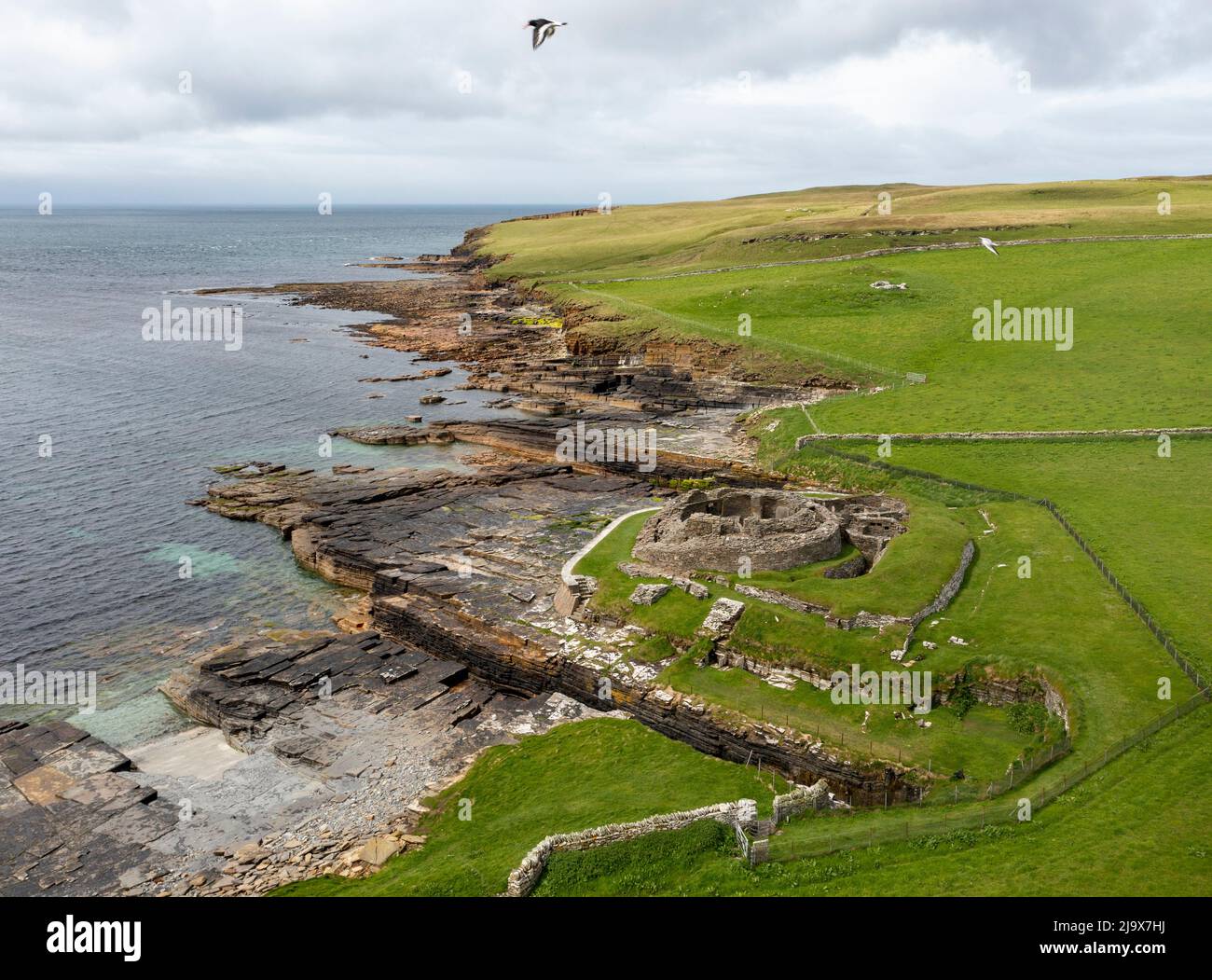 Aerial view of Midhowe Iron Age Broch on the SW coast of Rousay Island overlooking Eynhallow Sound & Orkney Mainland, Scotland, UK Stock Photo