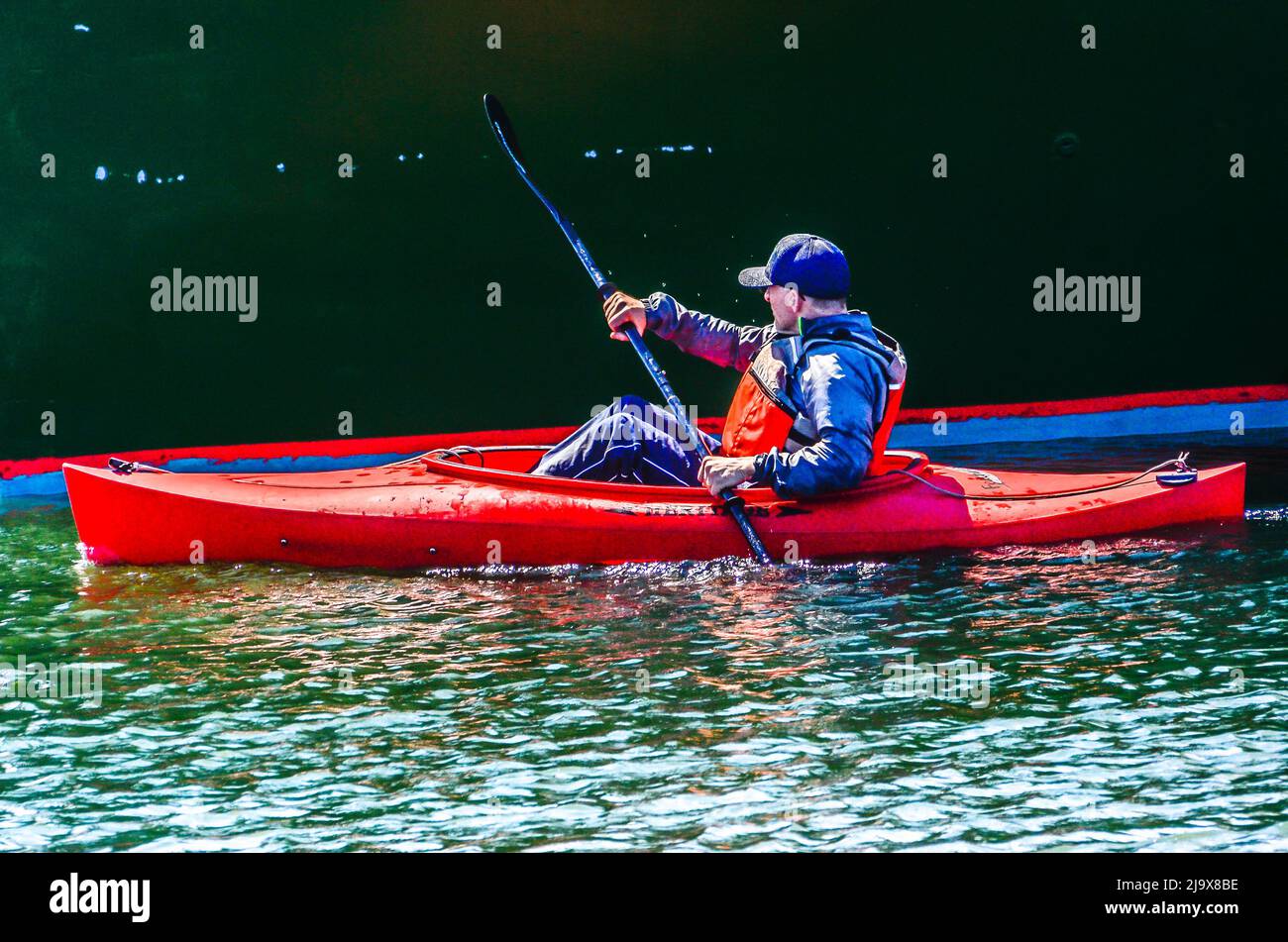 There may be a red line, but this man is no red liner, for sure. He just out to enjoy a ride in his Kayak and slowly paddle this Spring day away. Stock Photo