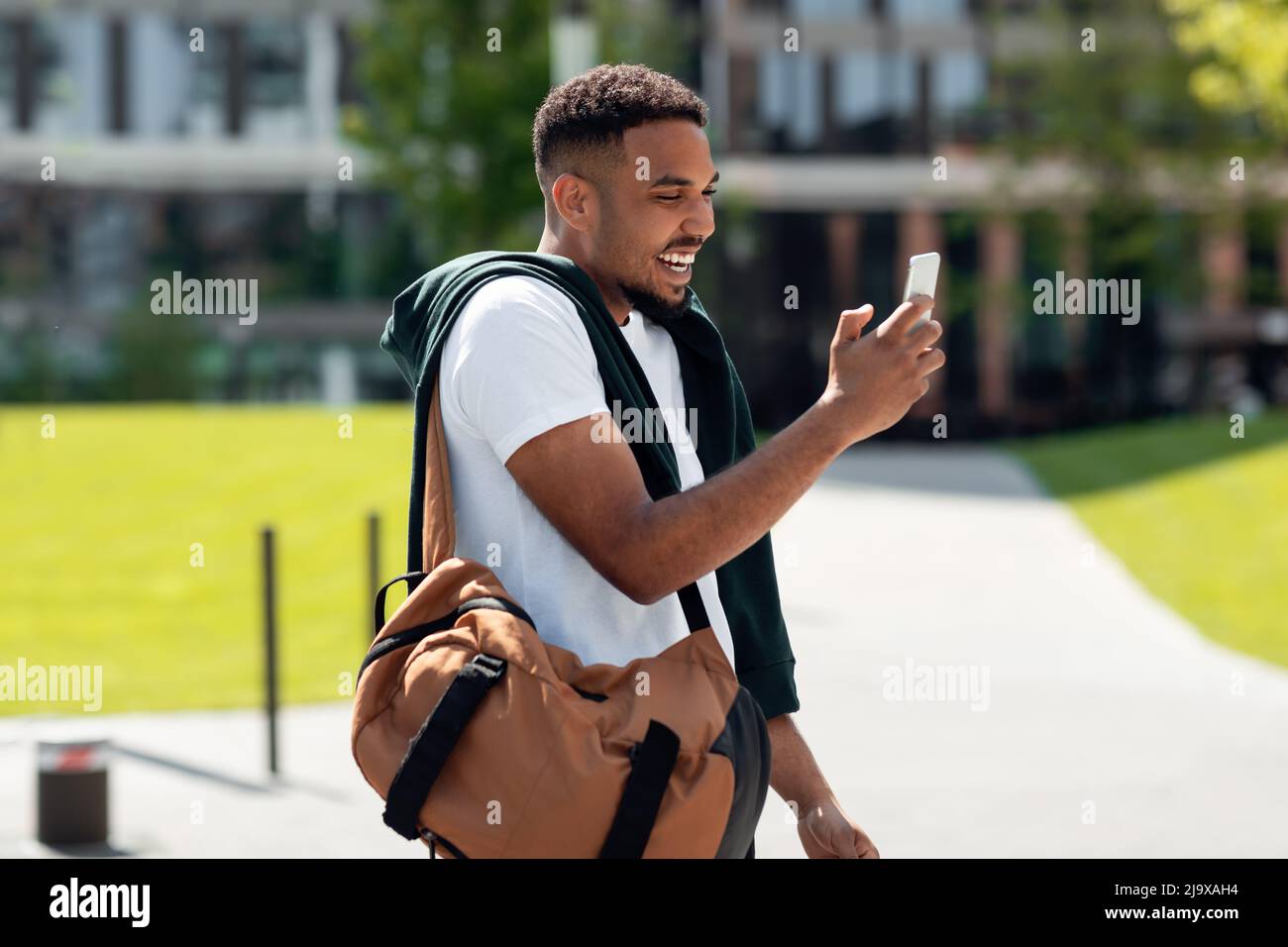 Smiling black man using phone walking in the city Stock Photo