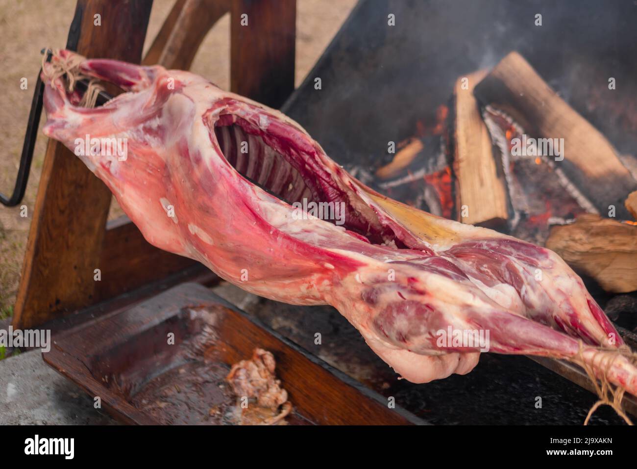 Process of cooking pork carcass on spit at summer street food market Stock Photo