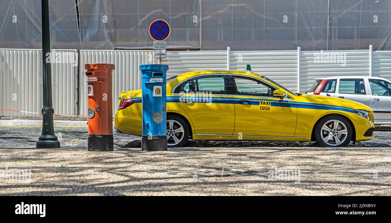 A yellow taxi set against the red and blue post boxes of the Madeira Postal Service. Red is for local mail and blue for international mail. Stock Photo