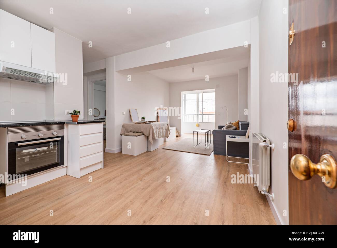 Entrance hall with open kitchen, living room with dining table with linen tablecloth and glazed terrace Stock Photo