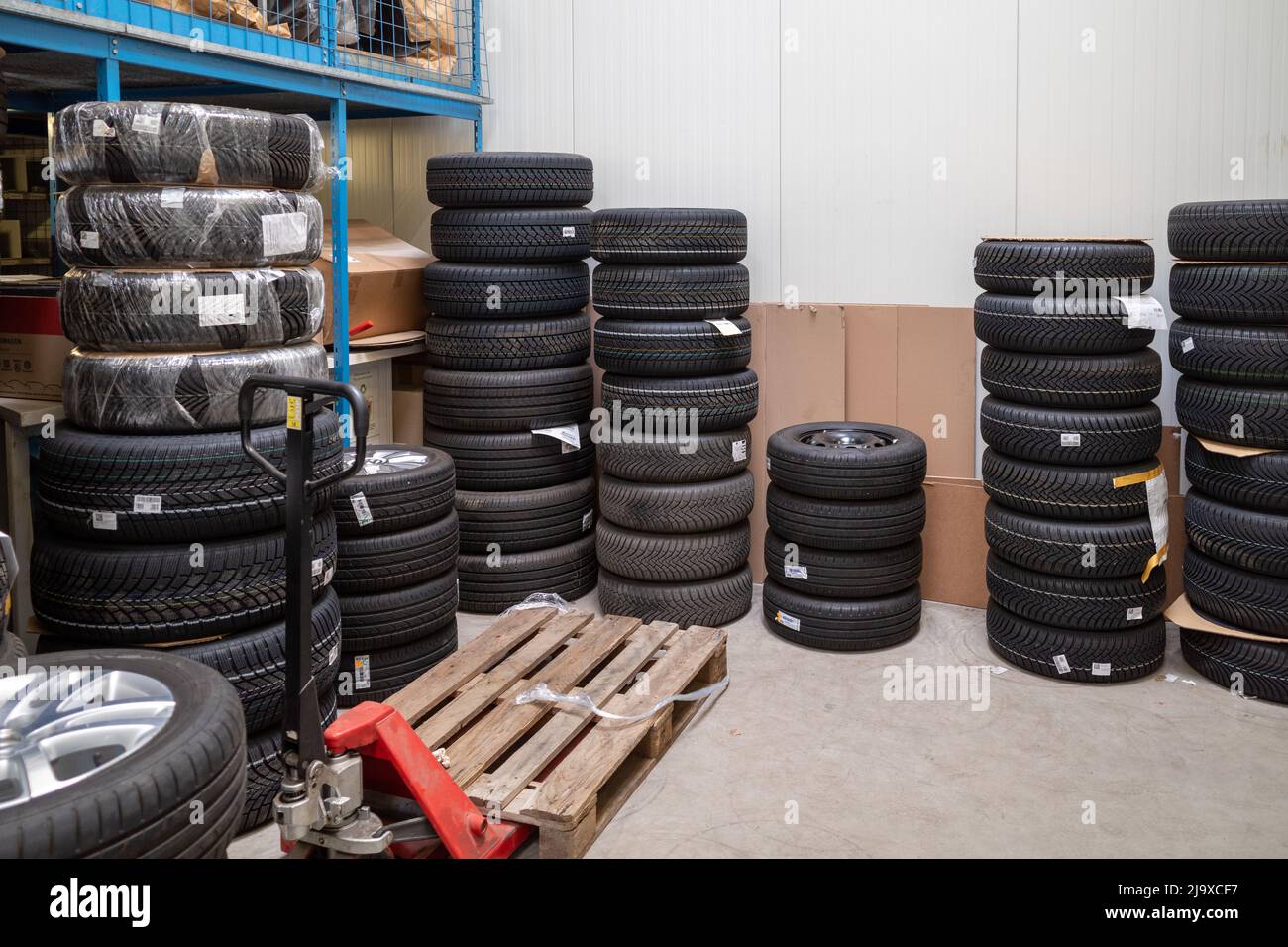 in the depot of a car repair shop there are many summer tires ready for