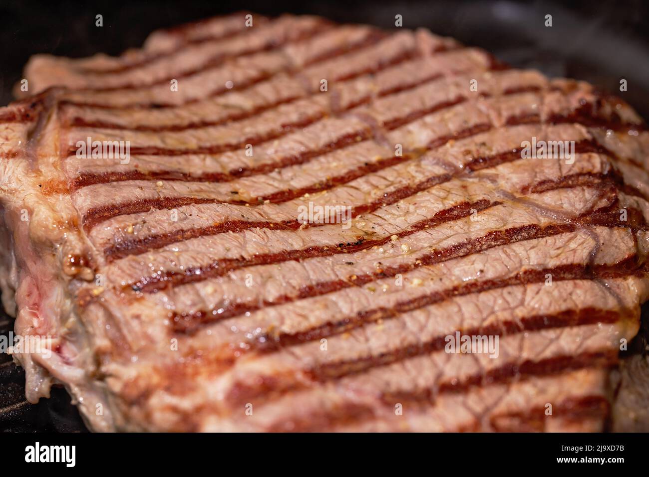 Closeup meat of beef steak grilled in castiron ribbed fry pan on gas