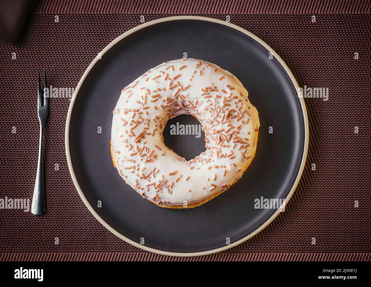 Tasty donut isolated on a plate on a fine table. Donuts, with white chocolate sprinkled with chocolate chips, Fine pastries Stock Photo