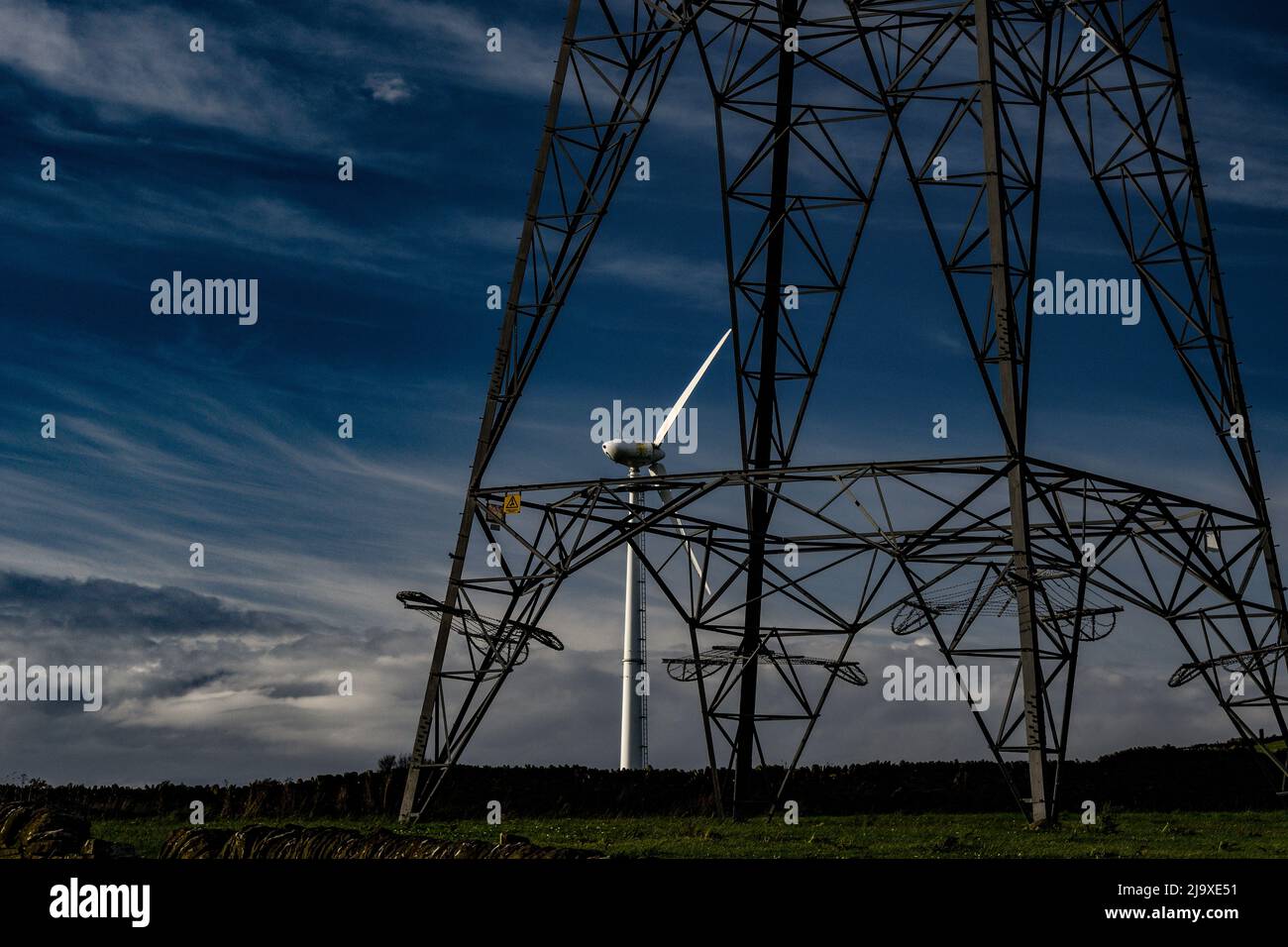 Electricity pylon on the moors above Stocksbridge near Sheffield, with a wind turbin behind. Stock Photo