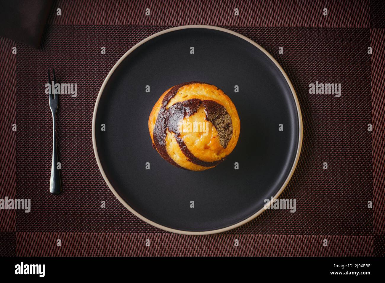 Vanilla Muffin with chocolate marbled on brown paper isolated on a thin plate on a nice table, fine pastries Stock Photo