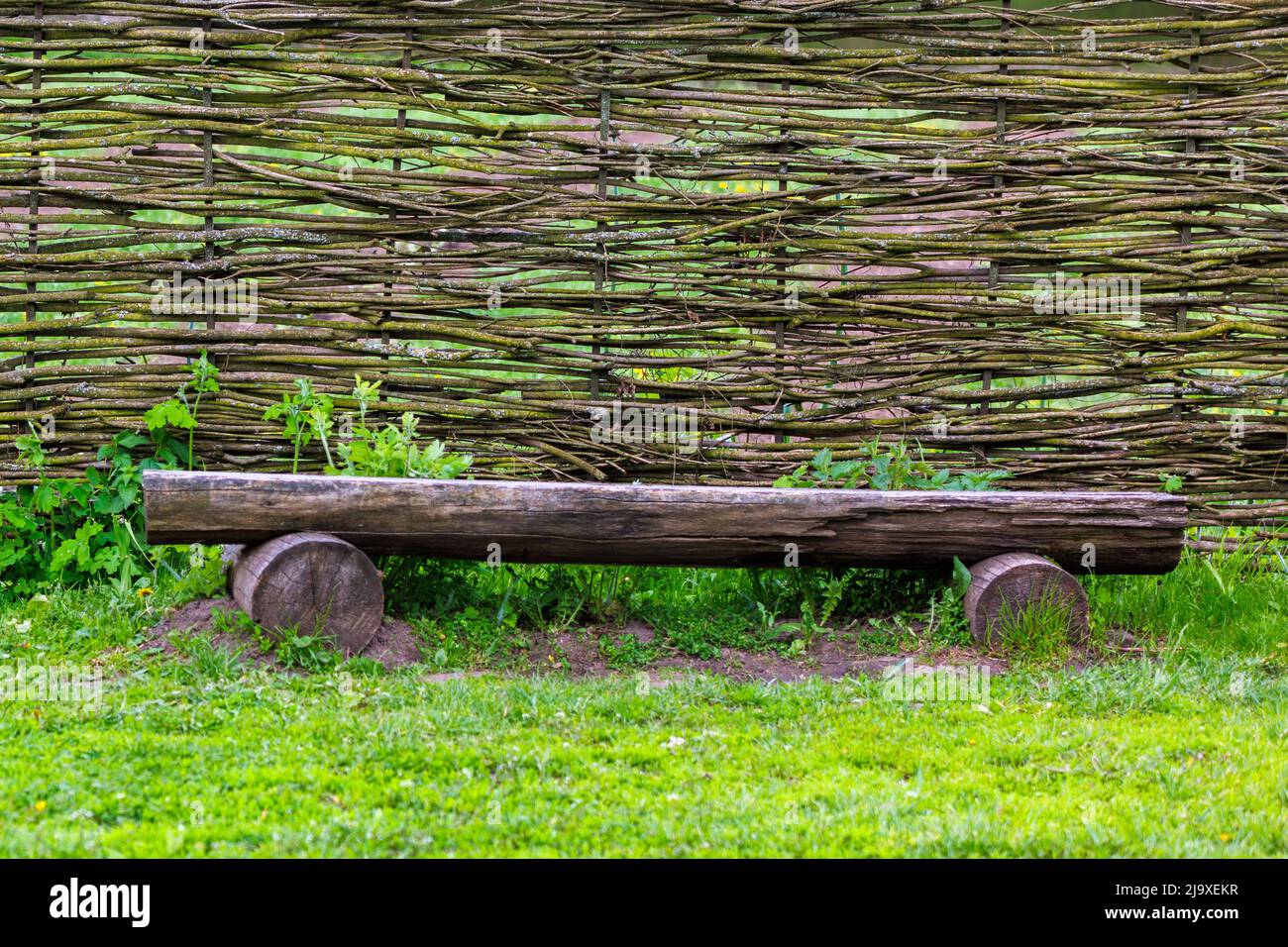 horizontal wattle fence with wooden bench near Stock Photo