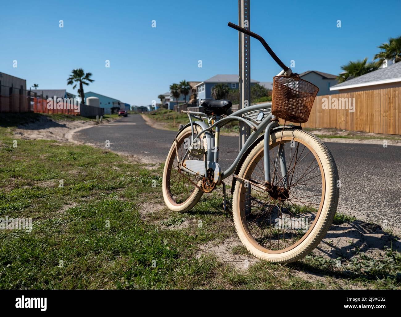 Old rusty bicycle leaning against a street sign post on a sunny day. Stock Photo