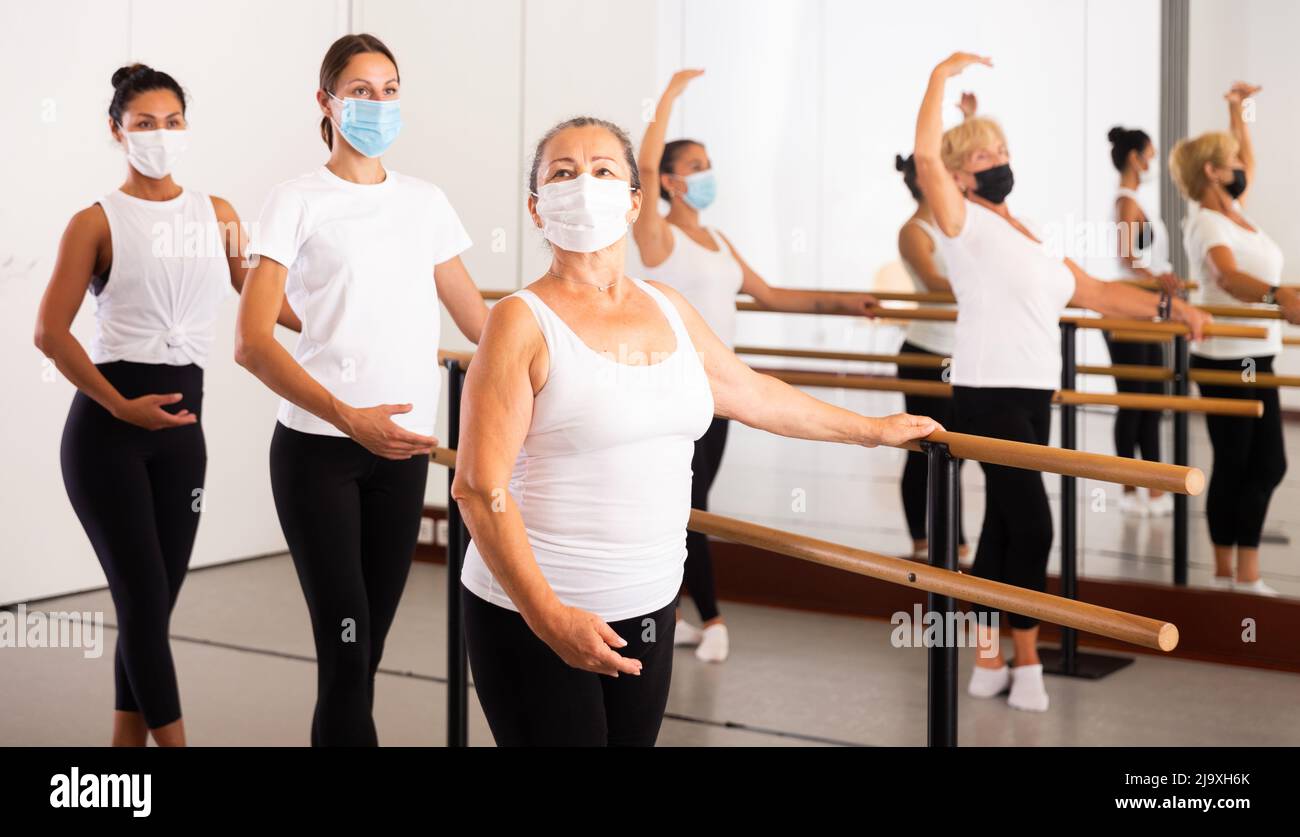 Women in masks exercising ballet moves in training room Stock Photo - Alamy