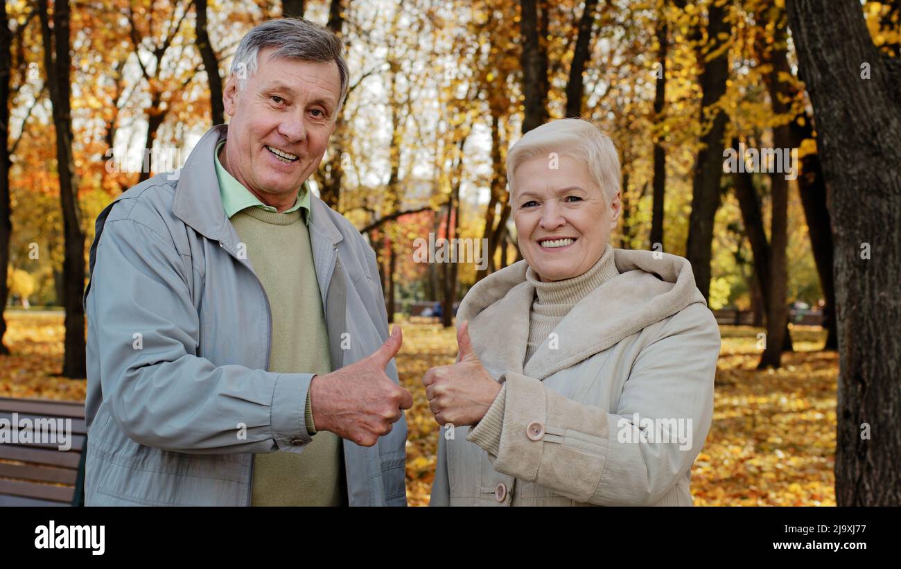 Portrait of happy elderly caucasian family wife husband senior grandparents stand outdoor in autumn park smiling old mature couple senior man woman Stock Photo