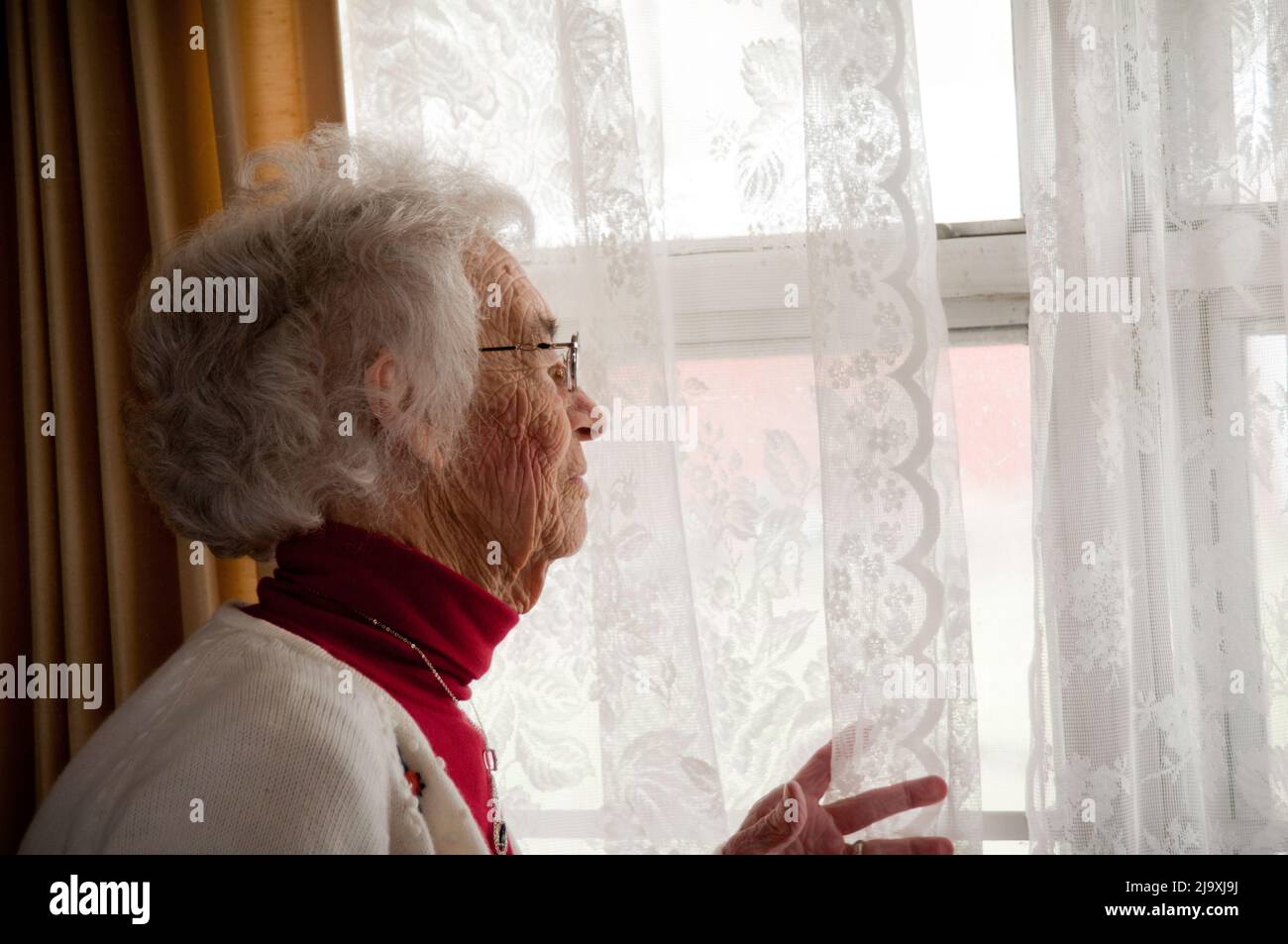 Elderly woman looking out of window Stock Photo