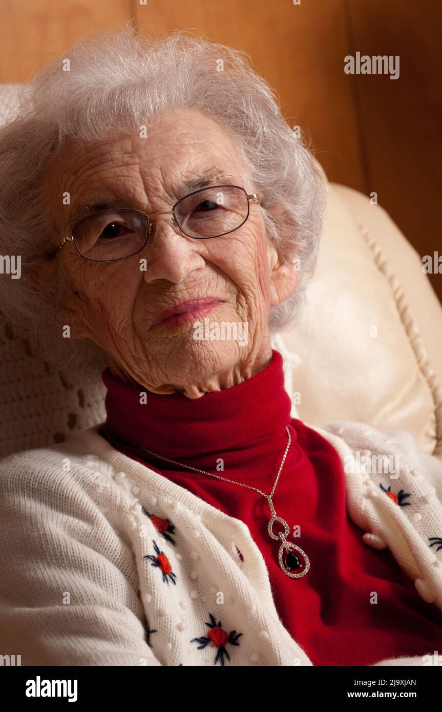Portrait of an elderly woman sitting on a chair and looking at the camera Stock Photo