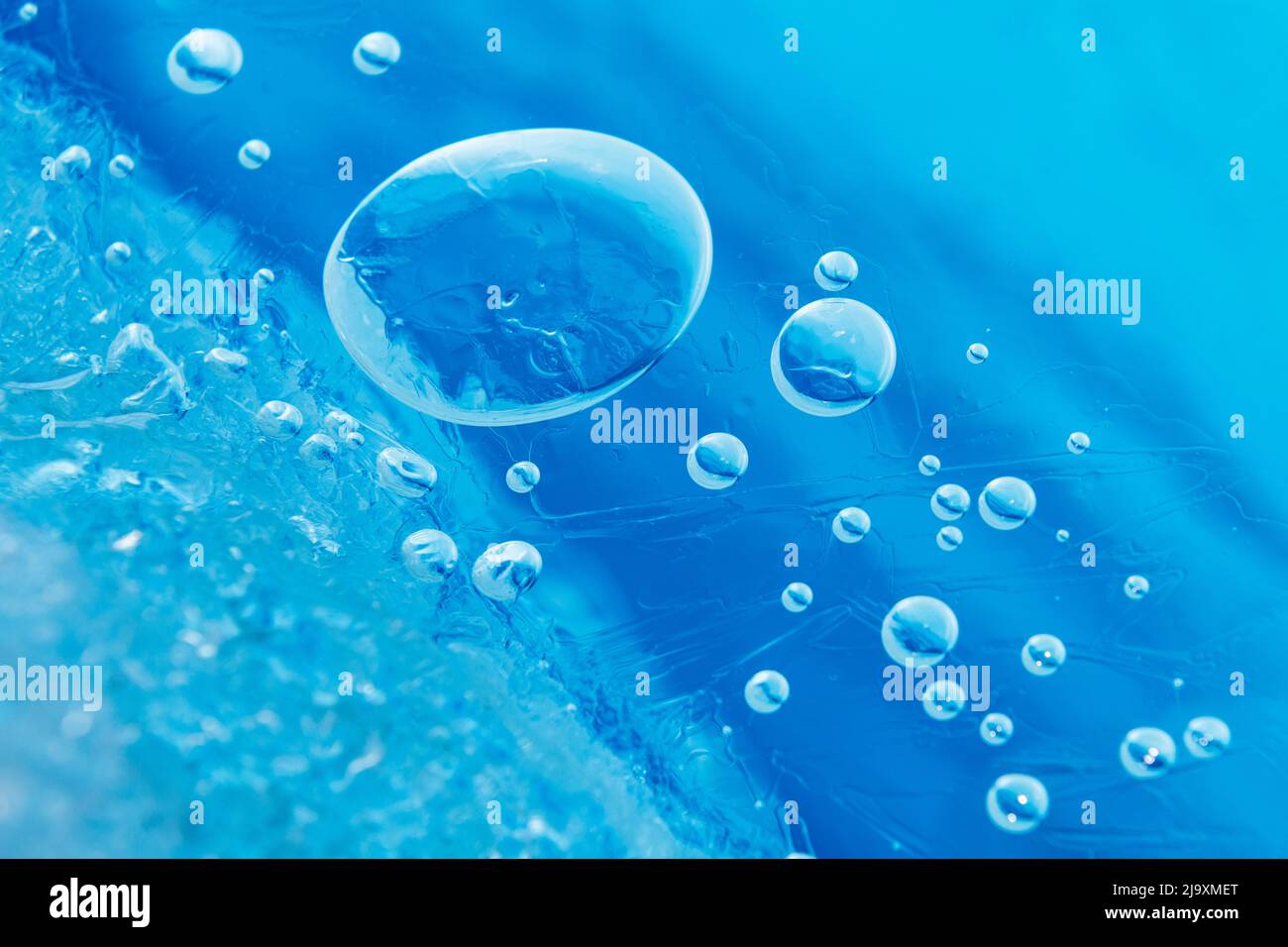 Small bubbles trapped under the ice in the brilliant blue water Stock