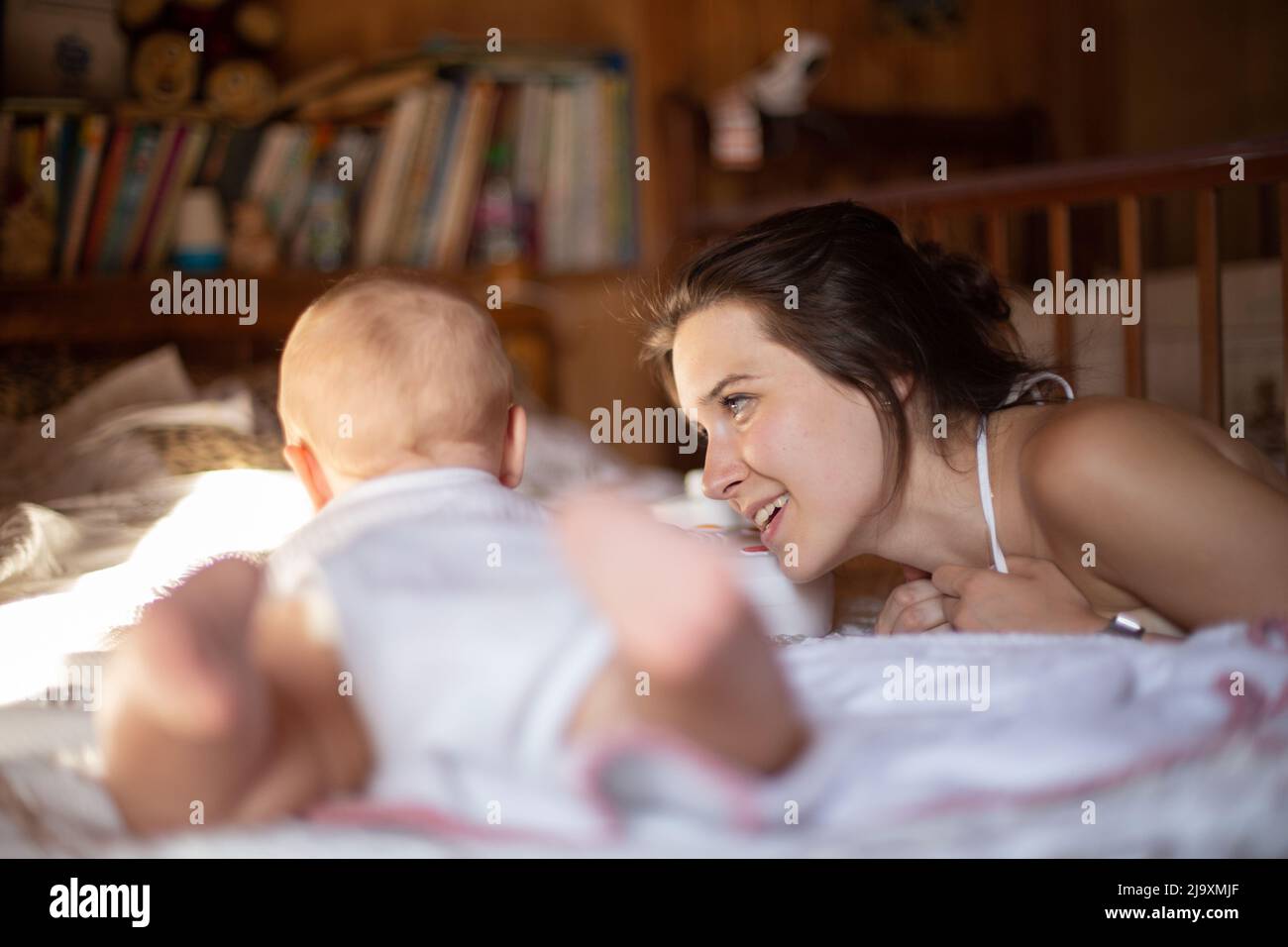 Mother lovingly looks at her baby in a cozy room Stock Photo