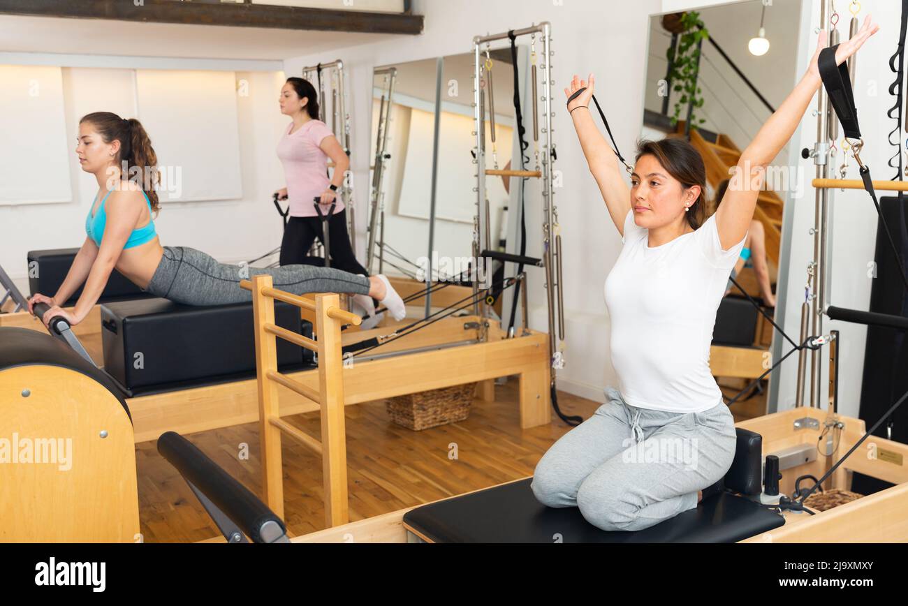 Young Latina practicing pilates on reformer at gym Stock Photo - Alamy