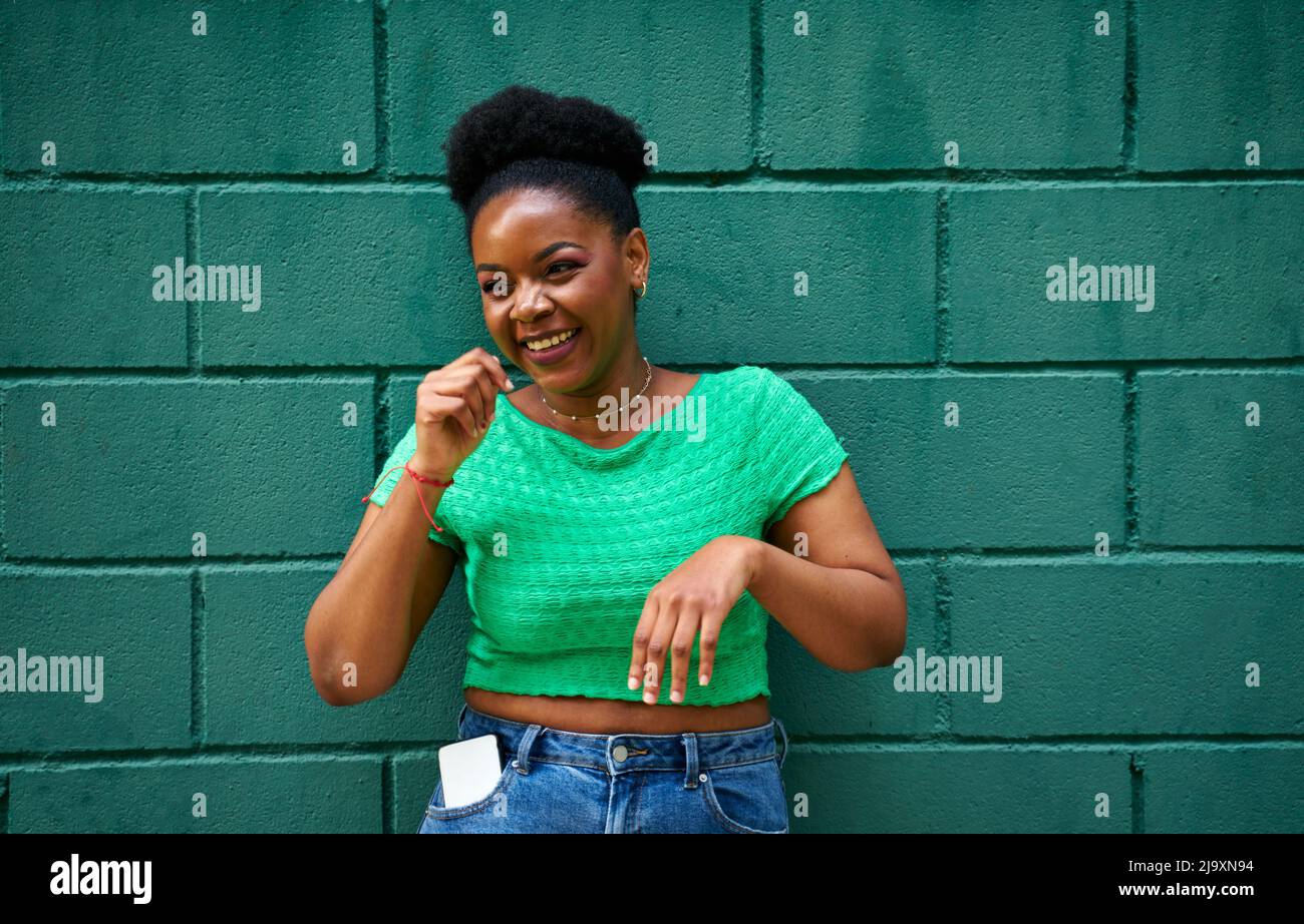 African american woman smiling on green wall Stock Photo - Alamy
