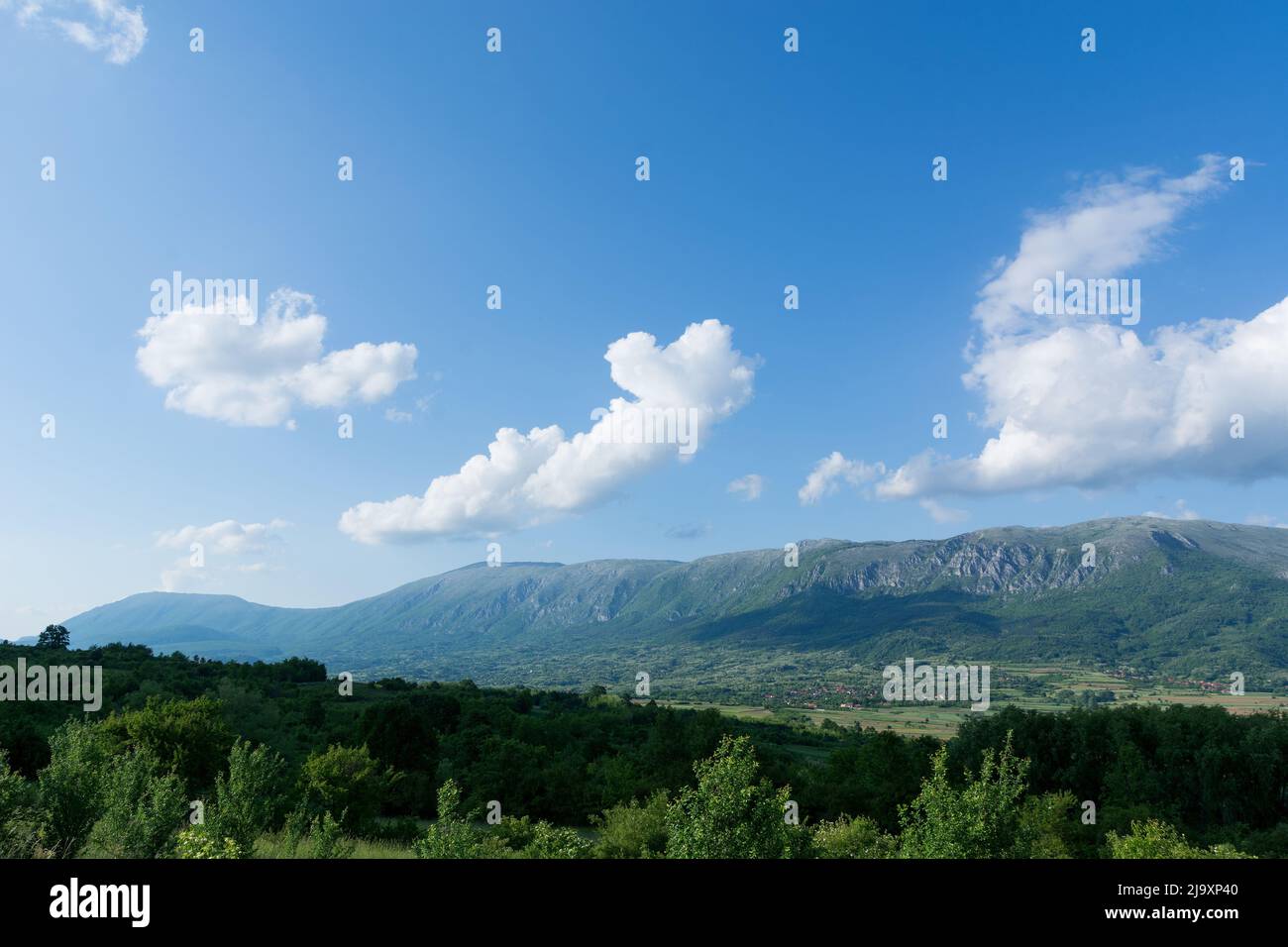 Beautiful landscape view of Suva Planina Dry Mountain in Serbia on a sunny spring day. White clouds cast a shadow on the great mountain Stock Photo