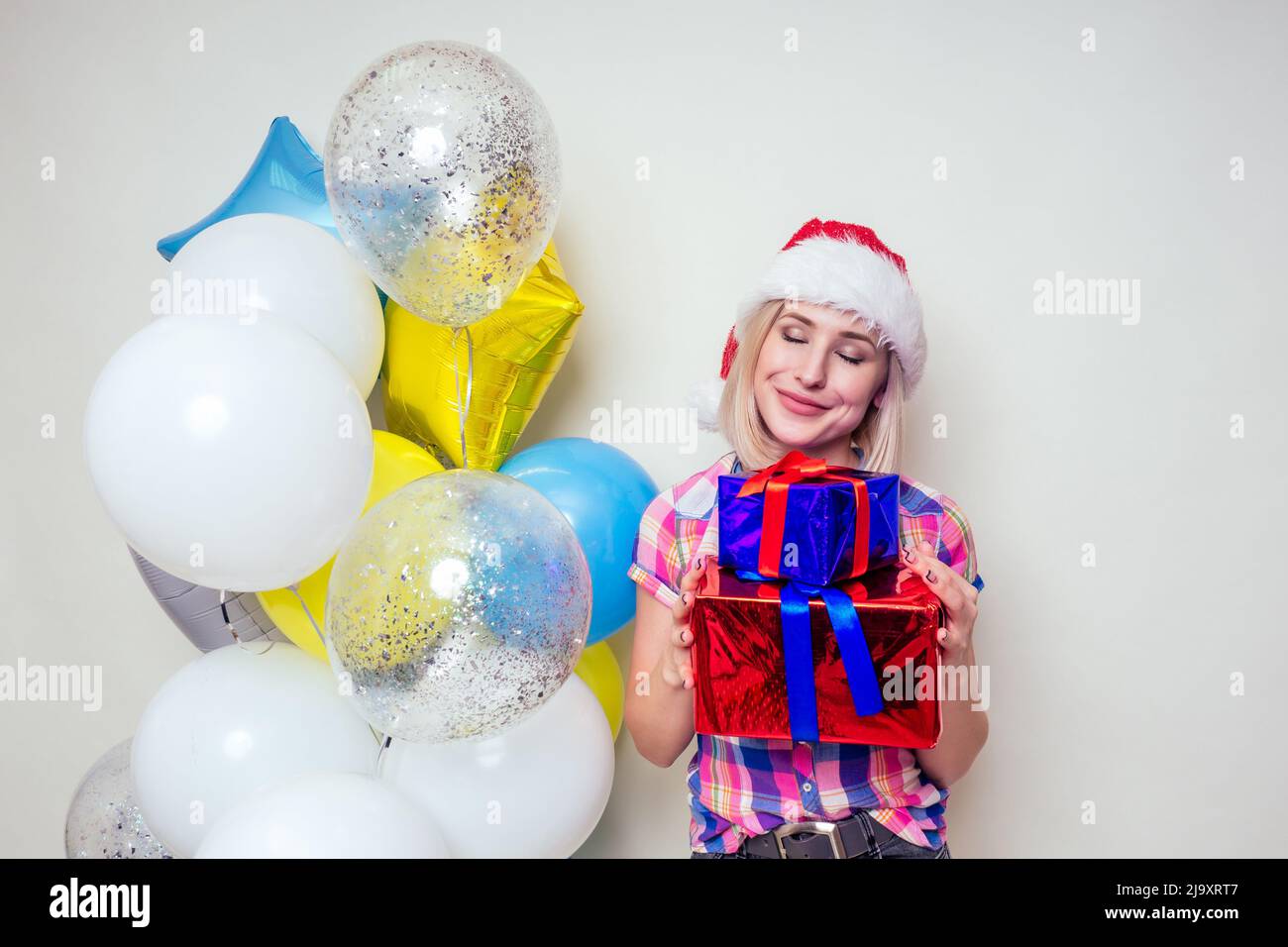 portrait of young Beautyful blondу amazed woman with christmas box gift on red background. lady in a plaid shirt and santa claus hold a bag full of Stock Photo