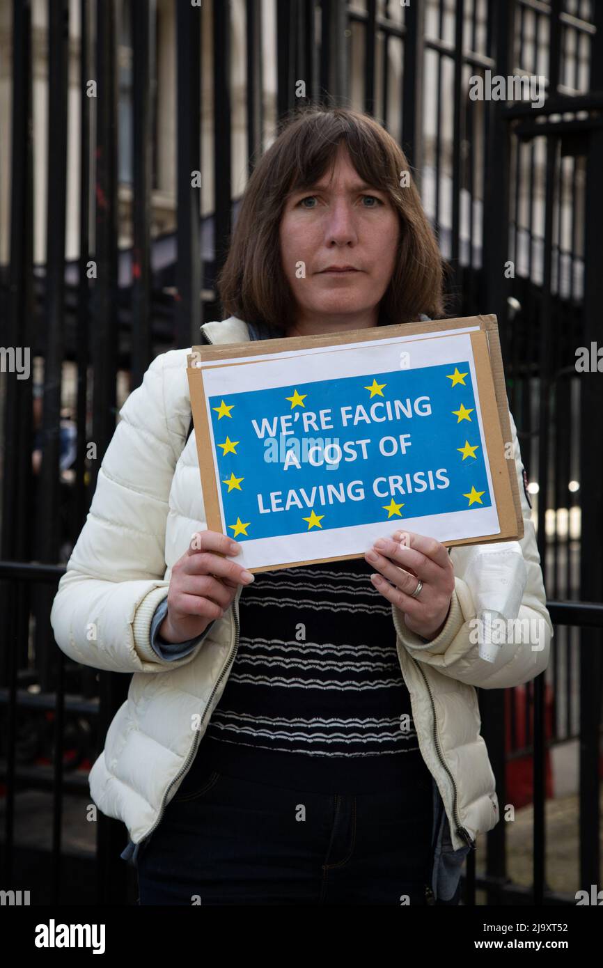 London, UK. 25 May 2022. A female protester from the Stand of Defiance European Movement (SODEM) holds up a sign outside Downing Street stating 'We're facing a cost of leaving crisis' referring to the rising cost of living in the country as a consequence of Brexit.. Credit: Kiki Streitberger/Alamy Live News Stock Photo