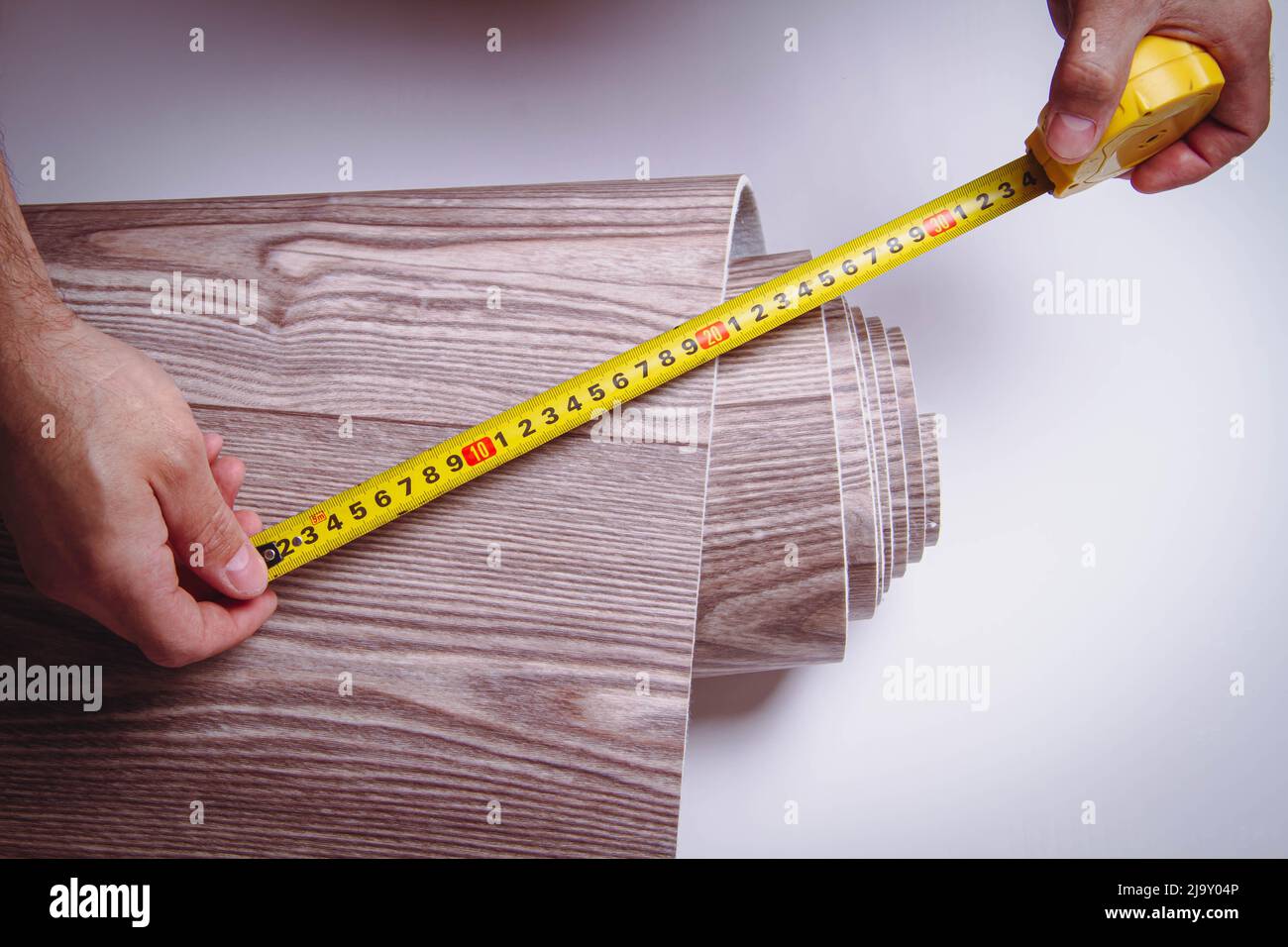Measurement of linoleum on a cut. Man cuts linoleum. Tape measure and a man's hand with a piece