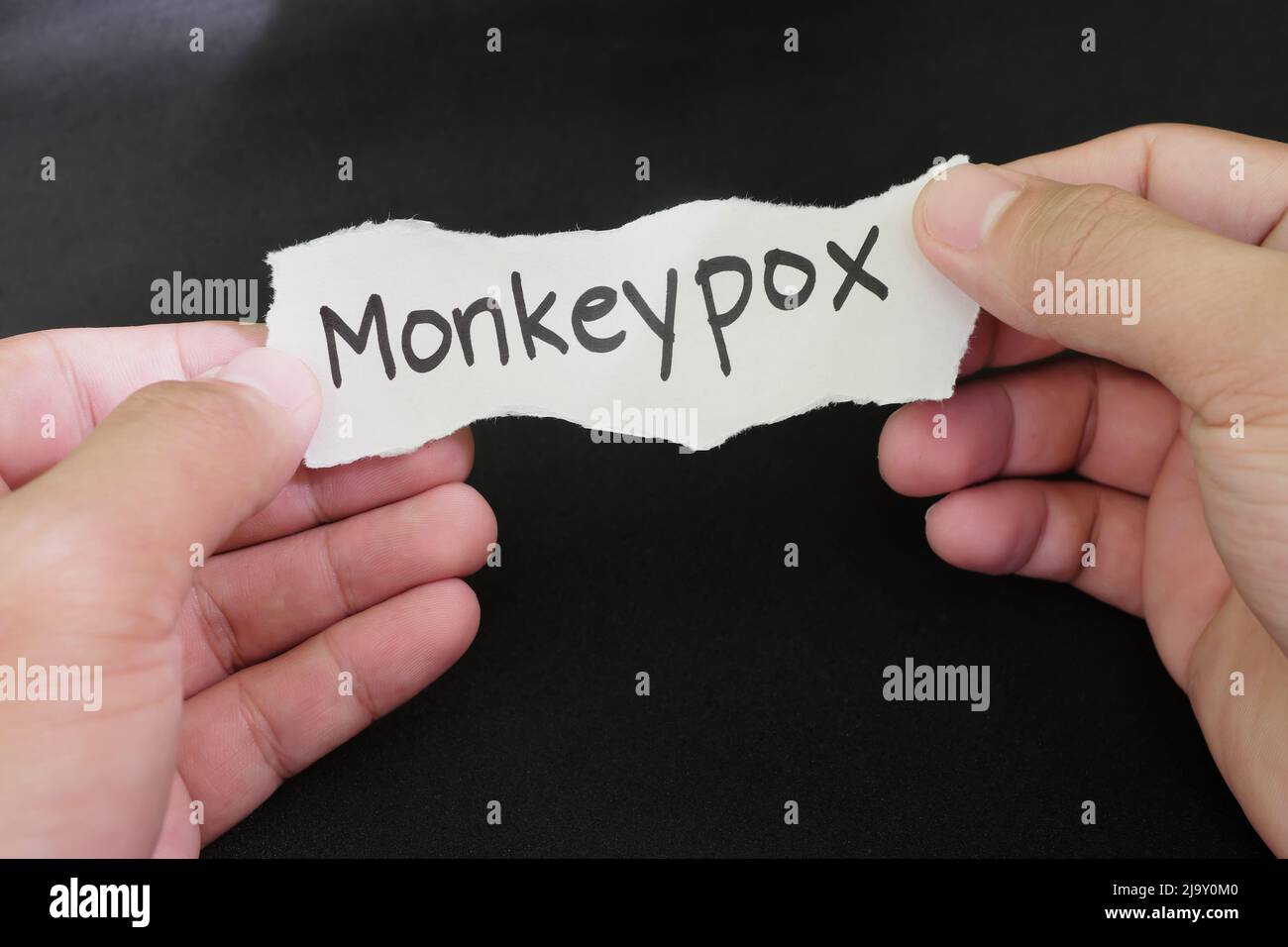 Monkeypox virus disease concept. Hand holding paper with word monkeypox in black background. Stock Photo