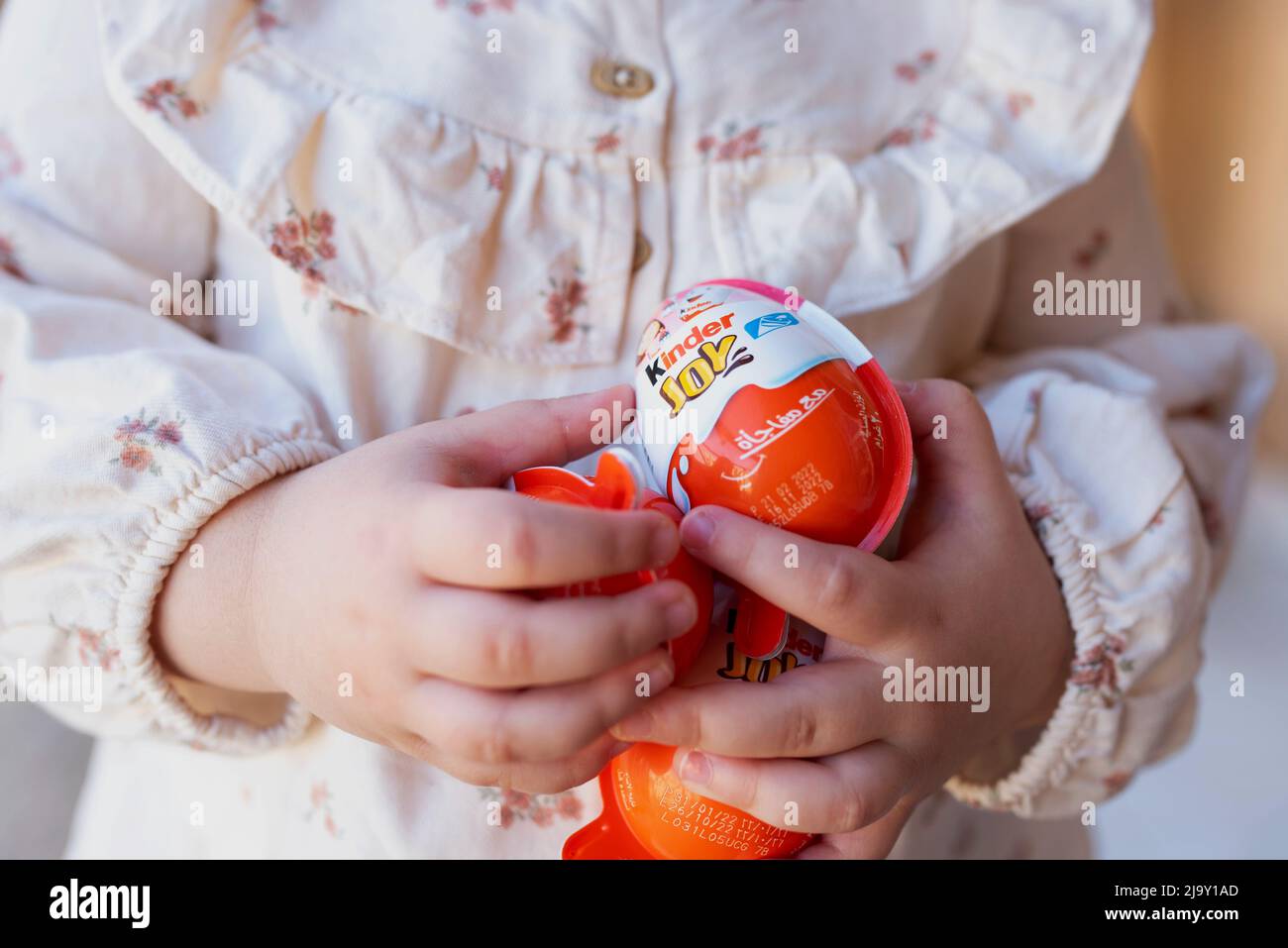 Cairo Egypt. 22. April 2022 Small girl holds chocolate Kinder Surprise Egg. Tasty chocolate present for child. sweet tooth. Stock Photo