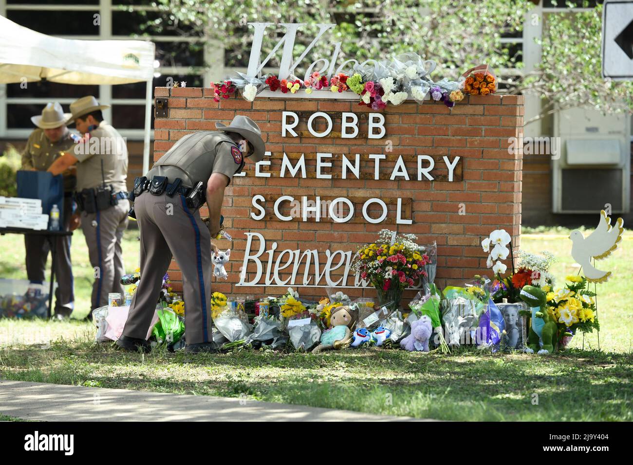 Uvalde, United States. 25th May, 2022. A Texas Dept. of Public Safety officer places memorials outside Robb Elementary school in south Uvalde where a lone gunman killed 19 schoolchildren and 2 teachers on May 24, 2022 Credit: Bob Daemmrich/Alamy Live News Stock Photo