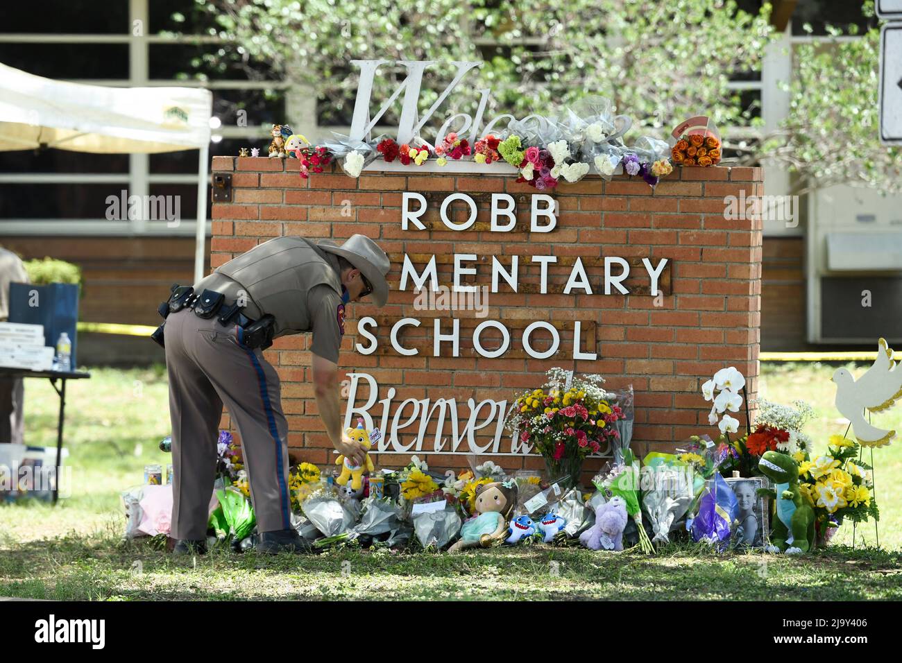 Uvalde, United States. 25th May, 2022. A Texas Dept. of Public Safety officer places memorials outside Robb Elementary school in south Uvalde where a lone gunman killed 19 schoolchildren and 2 teachers on May 24, 2022 Credit: Bob Daemmrich/Alamy Live News Stock Photo