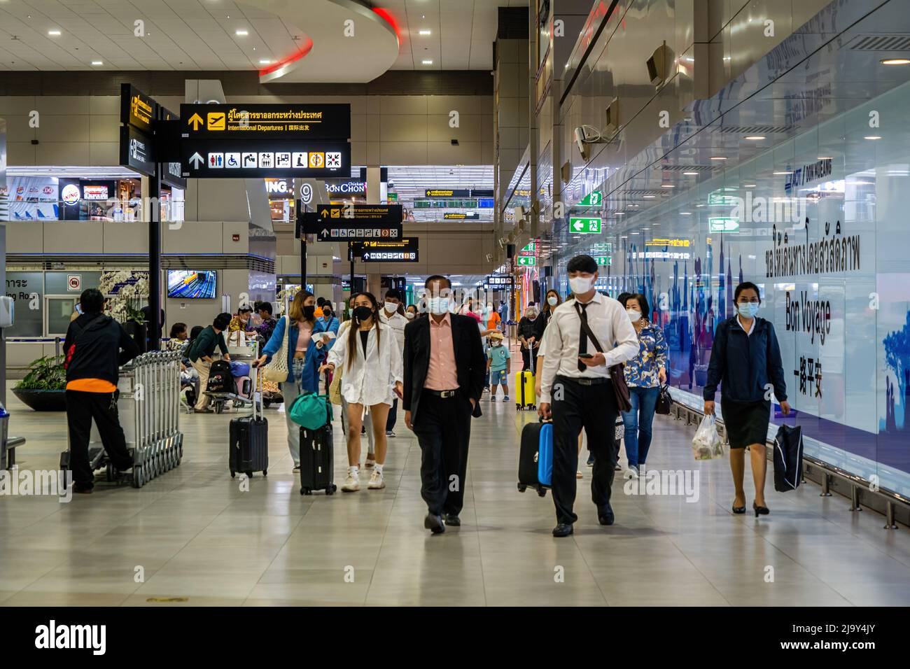 Travelers wearing face masks walk toward security checkpoints in the