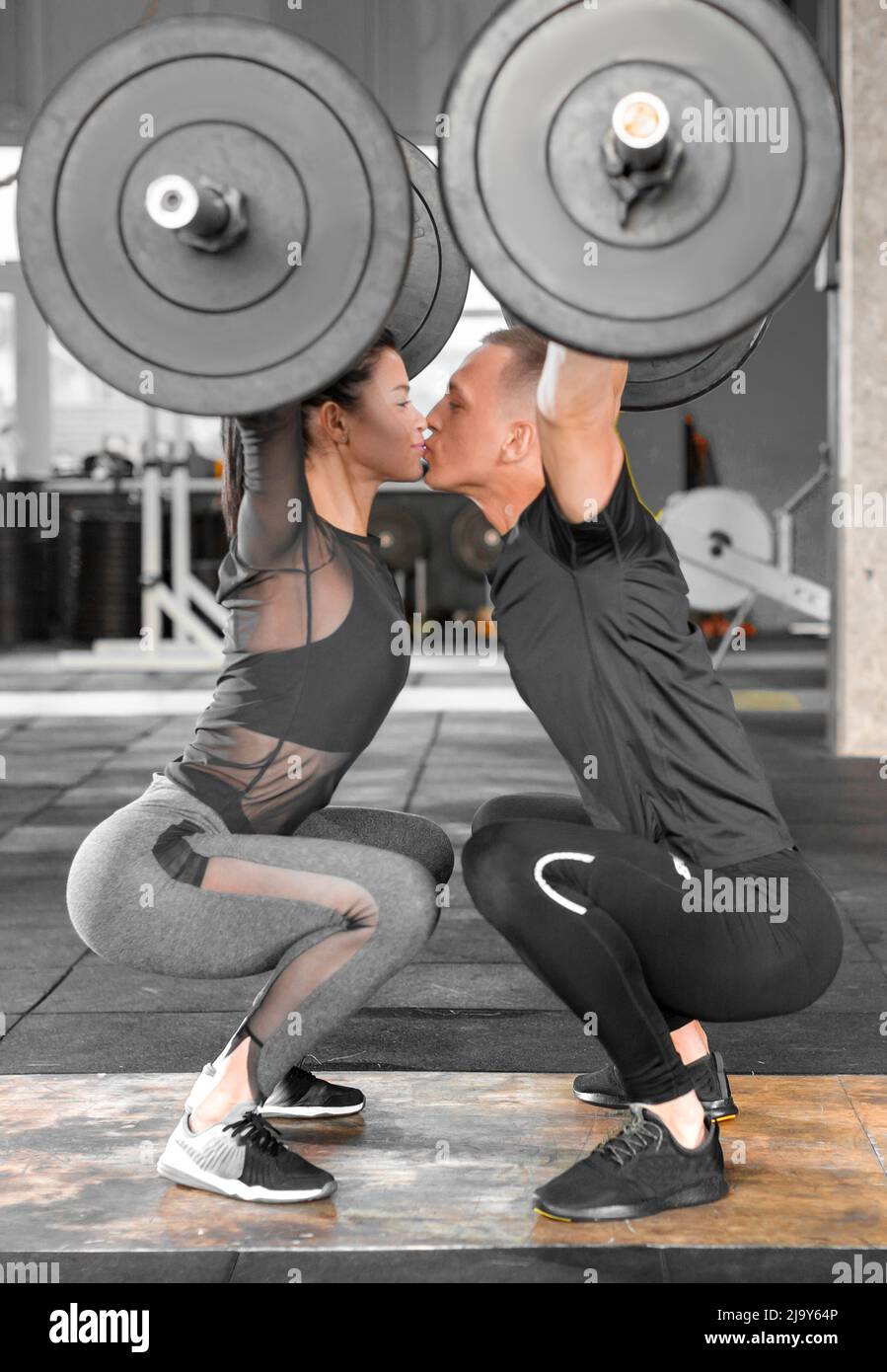 Fitness couple making a Barbell Jerk and kissing. Sporty family in gym.  Side view Stock Photo - Alamy