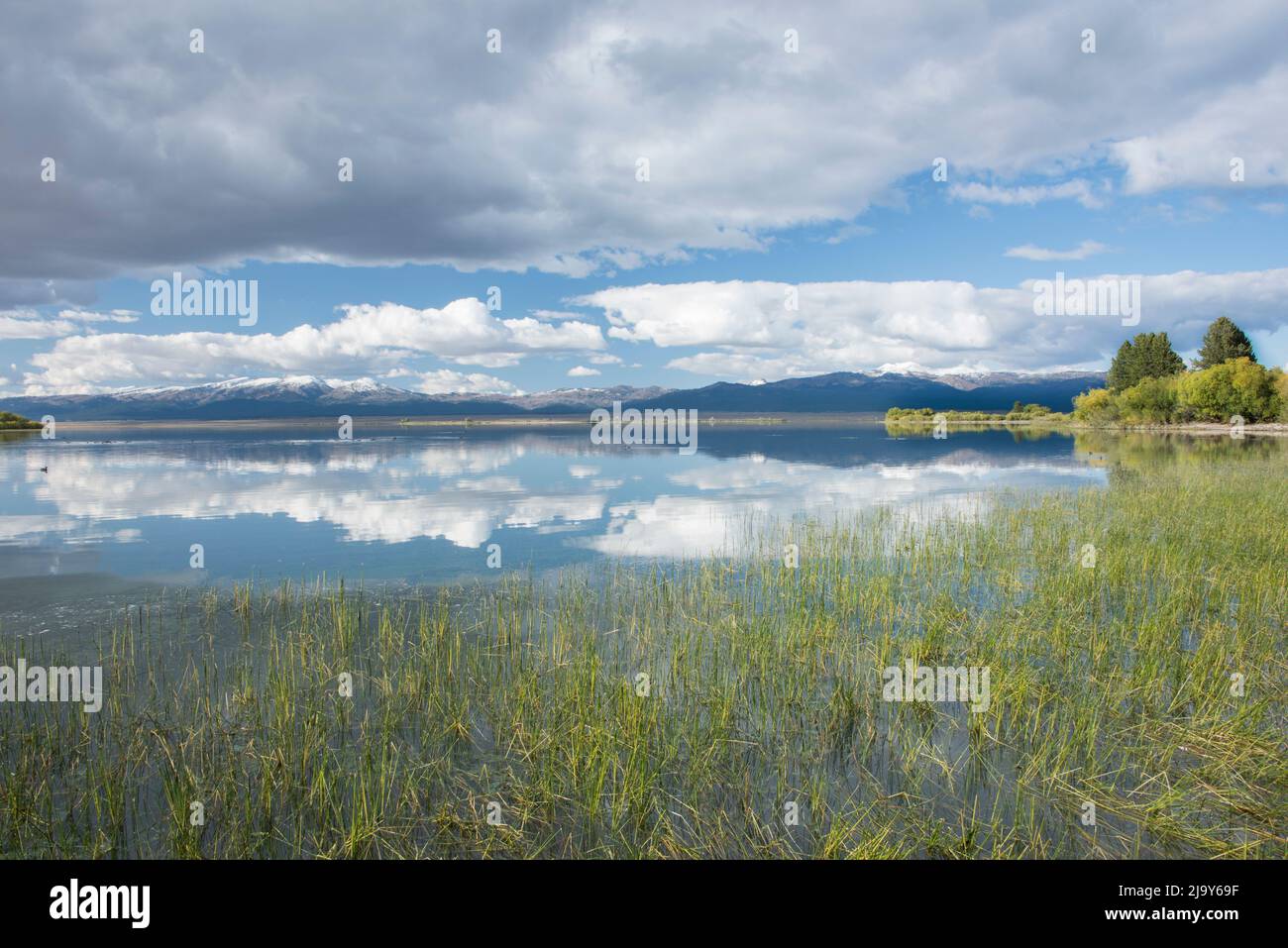 Puffy clouds and blue sky reflect in the still waters of Island Park