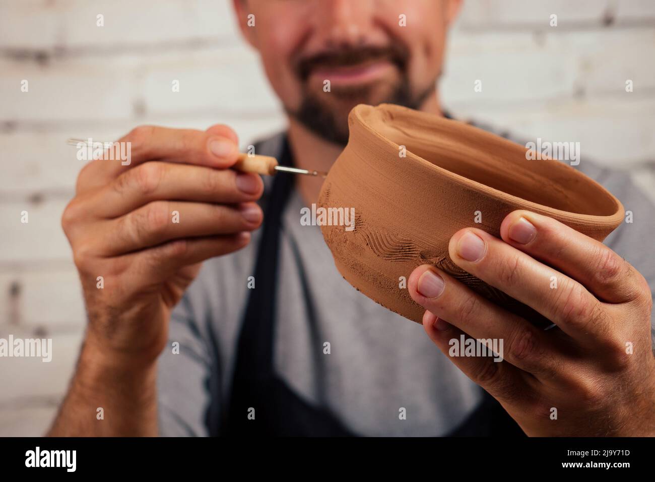 potter professional happy man working with brown clay in workshop