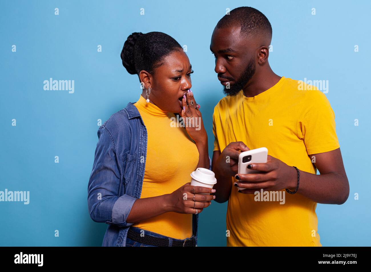 Shocked man and woman reading unexpected news on smartphone. Girlfriend ...