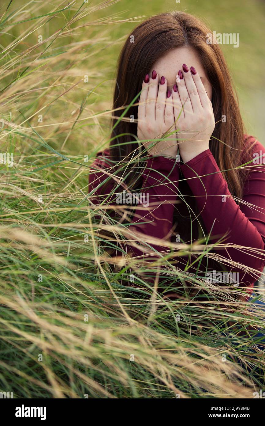 Woman hiding face with hands crying outdoors Stock Photo