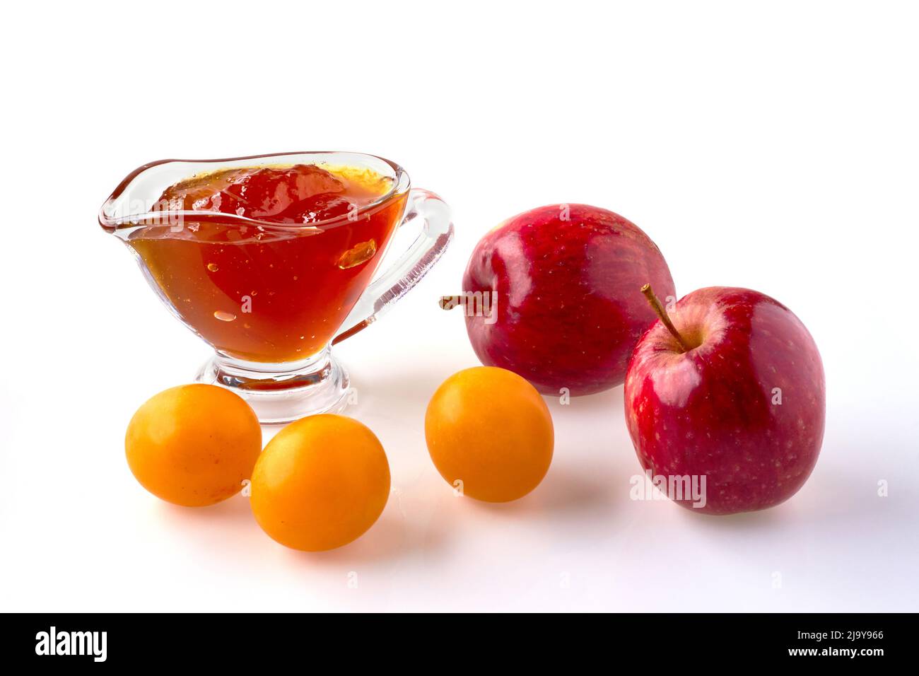 Red cherry plum apples and fruit jam in a glass gravy boat isolated on a white background Stock Photo
