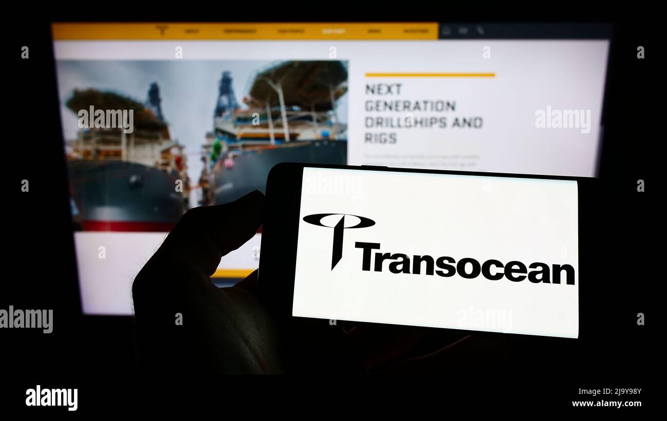 Person holding smartphone with logo of offshore drilling company Transocean Ltd. on screen in front of website. Focus on phone display. Stock Photo