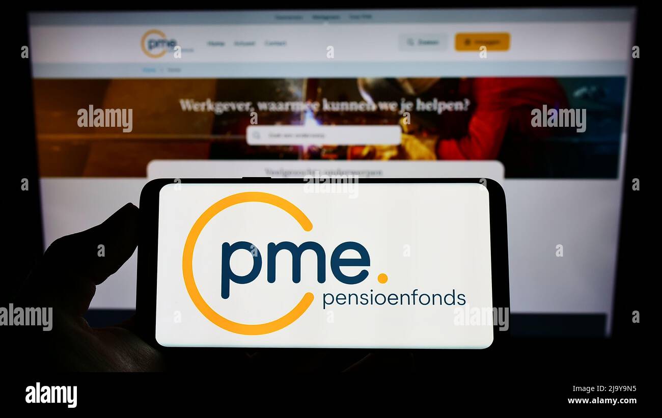 Person holding cellphone with logo of Dutch pension fund PME Pensioenfonds on screen in front of business webpage. Focus on phone display. Stock Photo