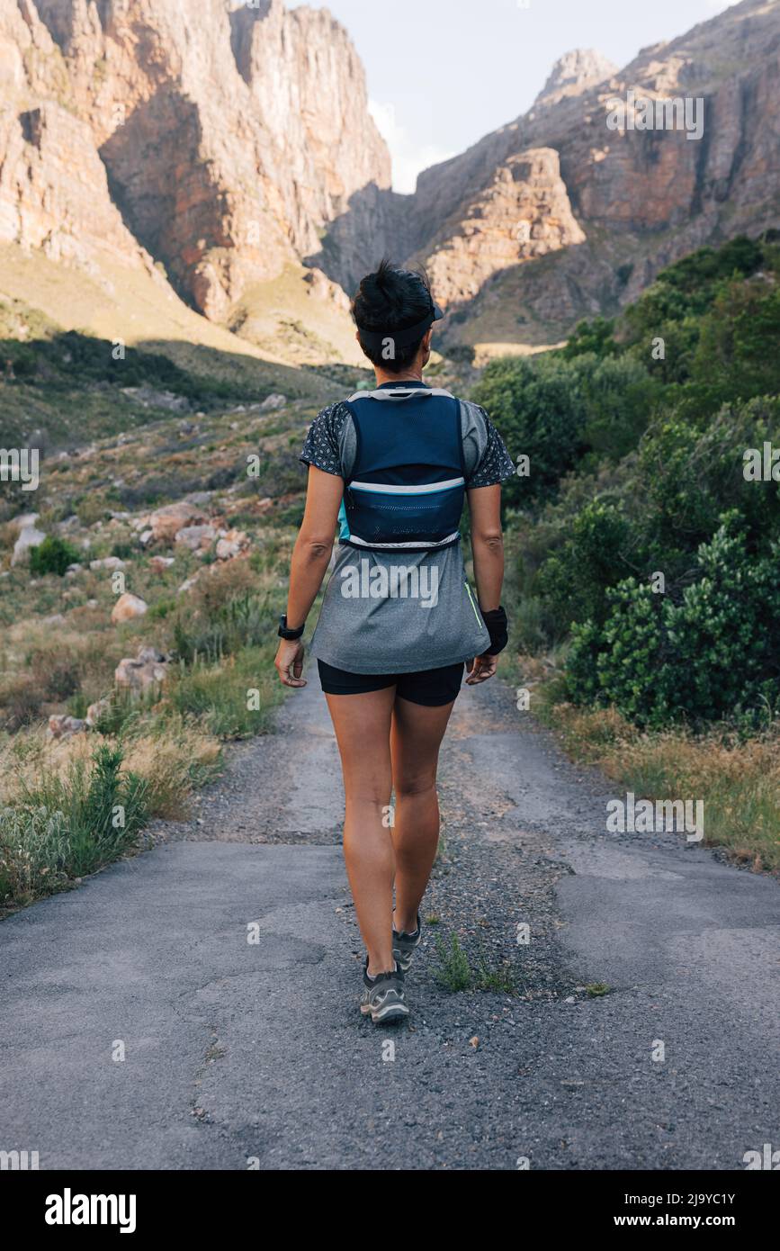 Back view of woman hiker walking on abandoned road in valley. Female ...